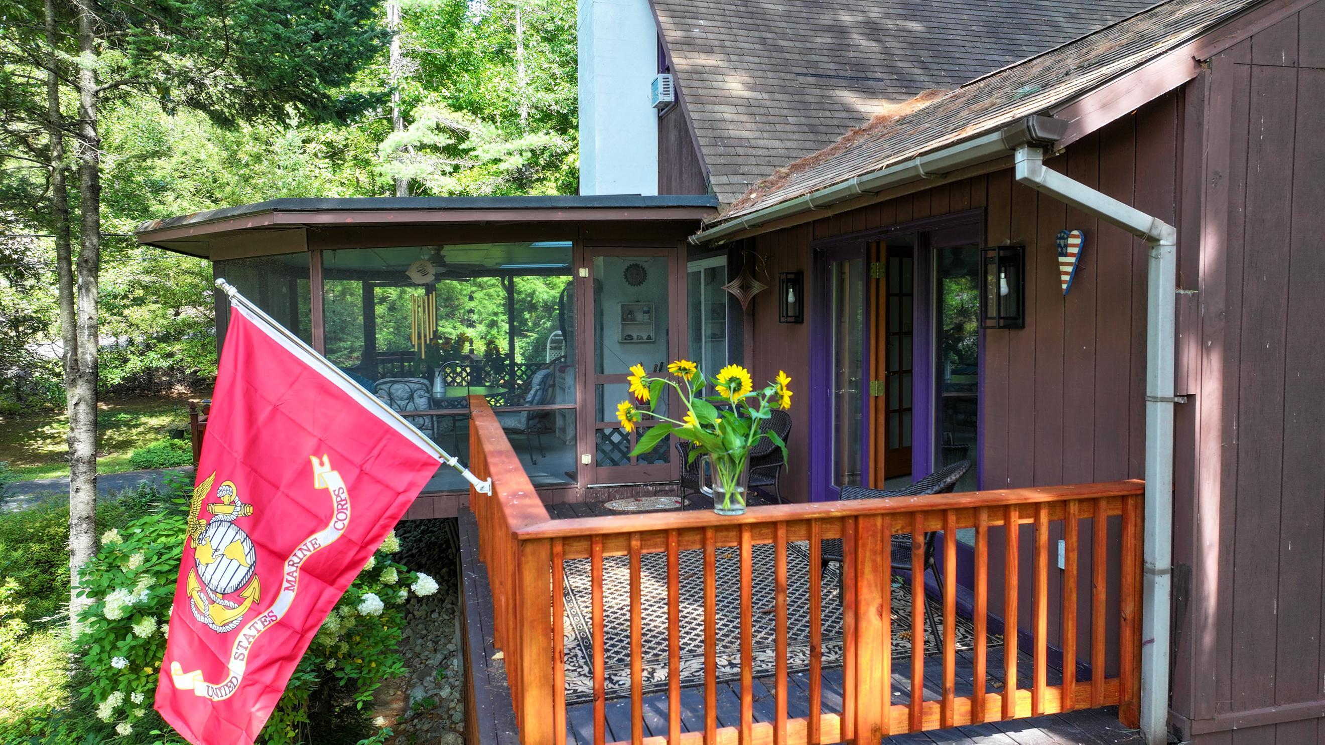 Brown home exterior with a screened porch, wooden deck railing, and Marine Corps flag.