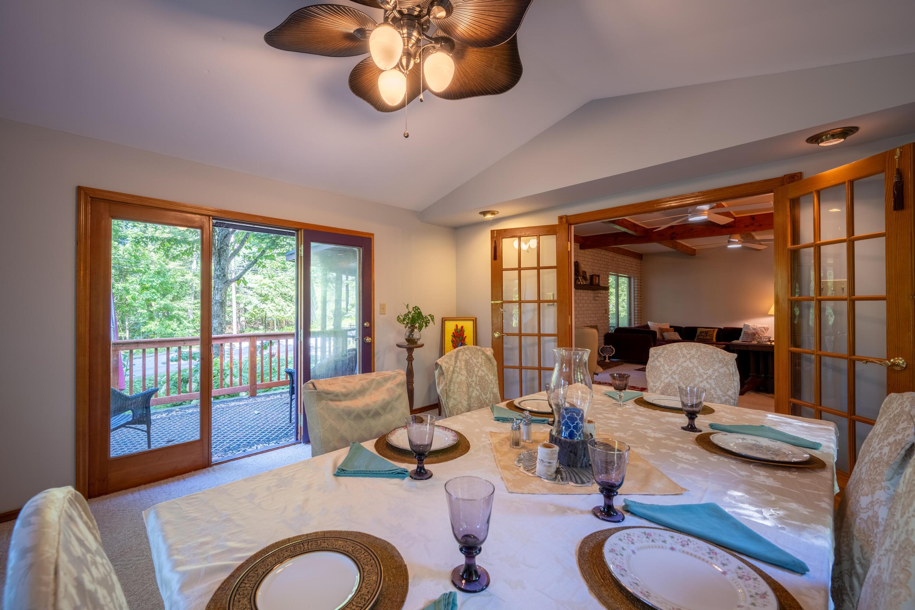 Dining room with a set table, wood-framed glass doors, and an adjoining living room.