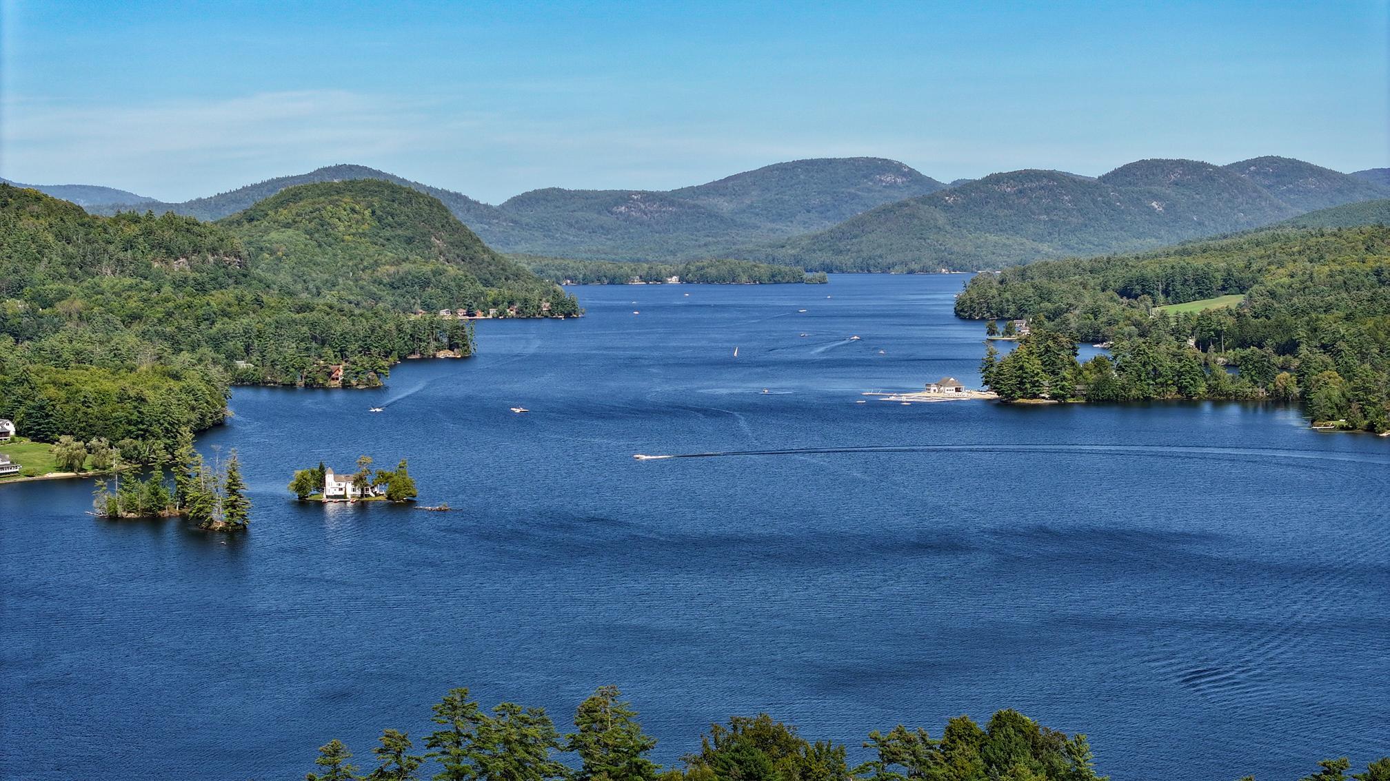 Panoramic lake view with wooded islands and forested mountains.