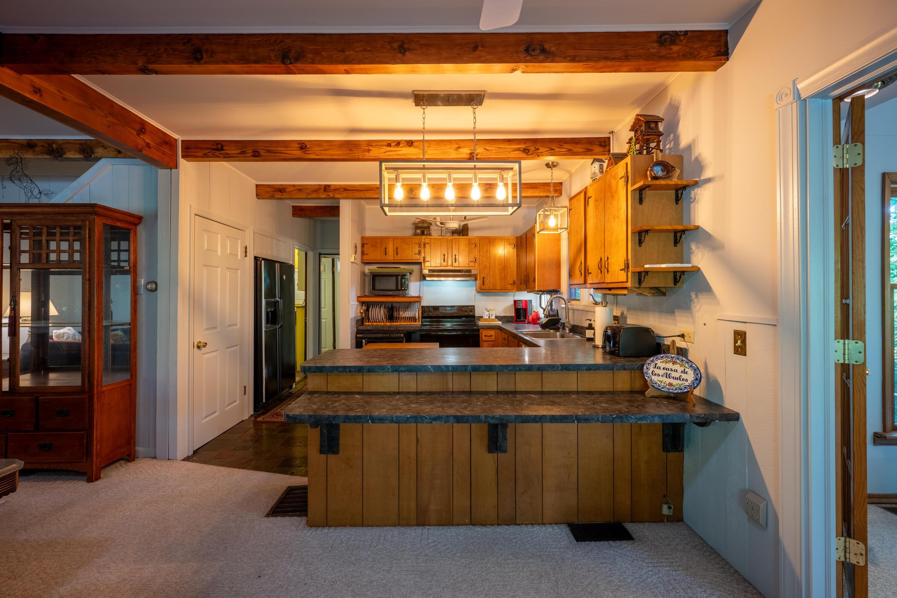 Kitchen with exposed timber beams, warm wood cabinets, and two stone-topped islands.