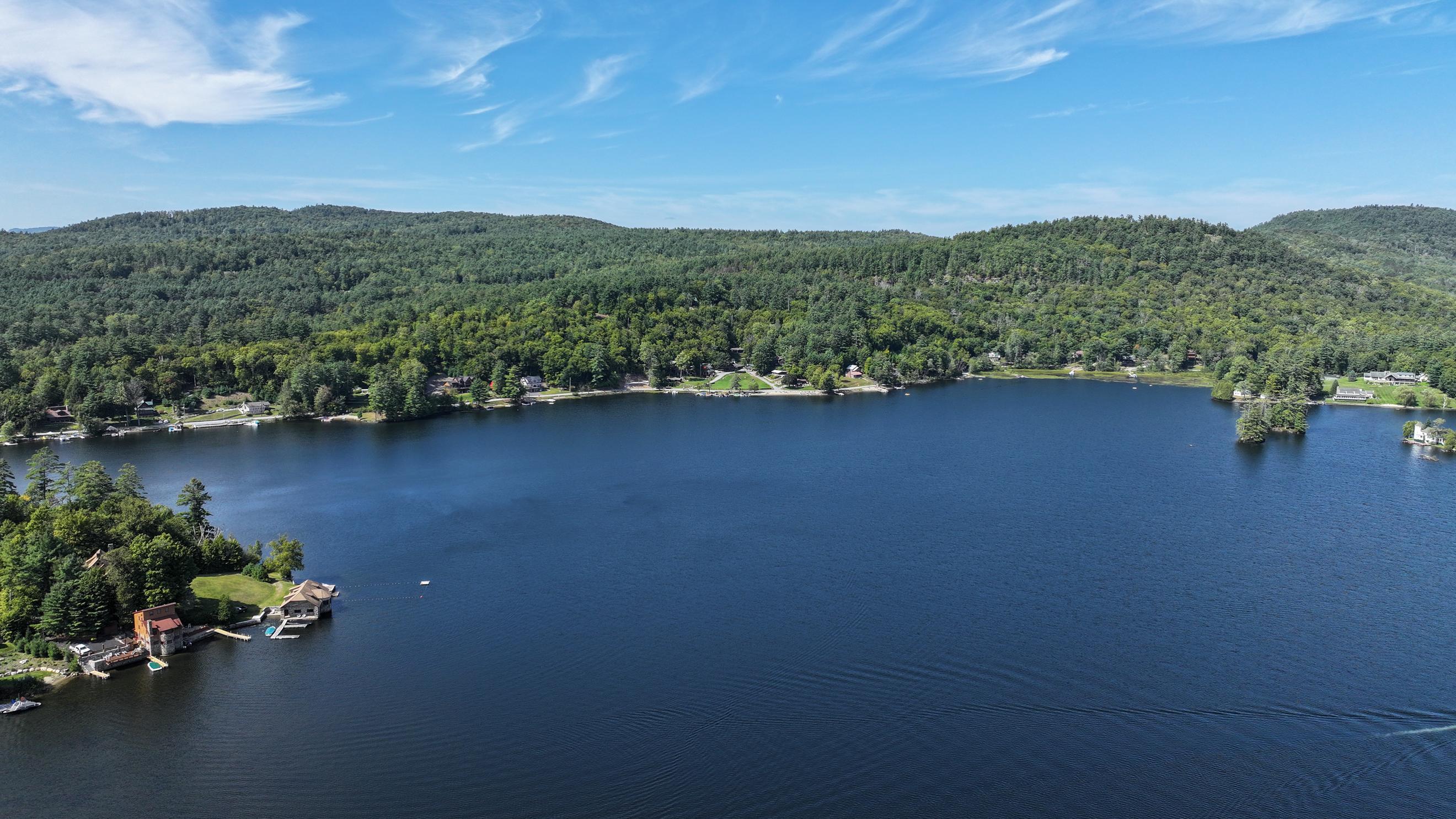 Aerial view of Brant Lake, with wooded hills and homes along the shoreline.