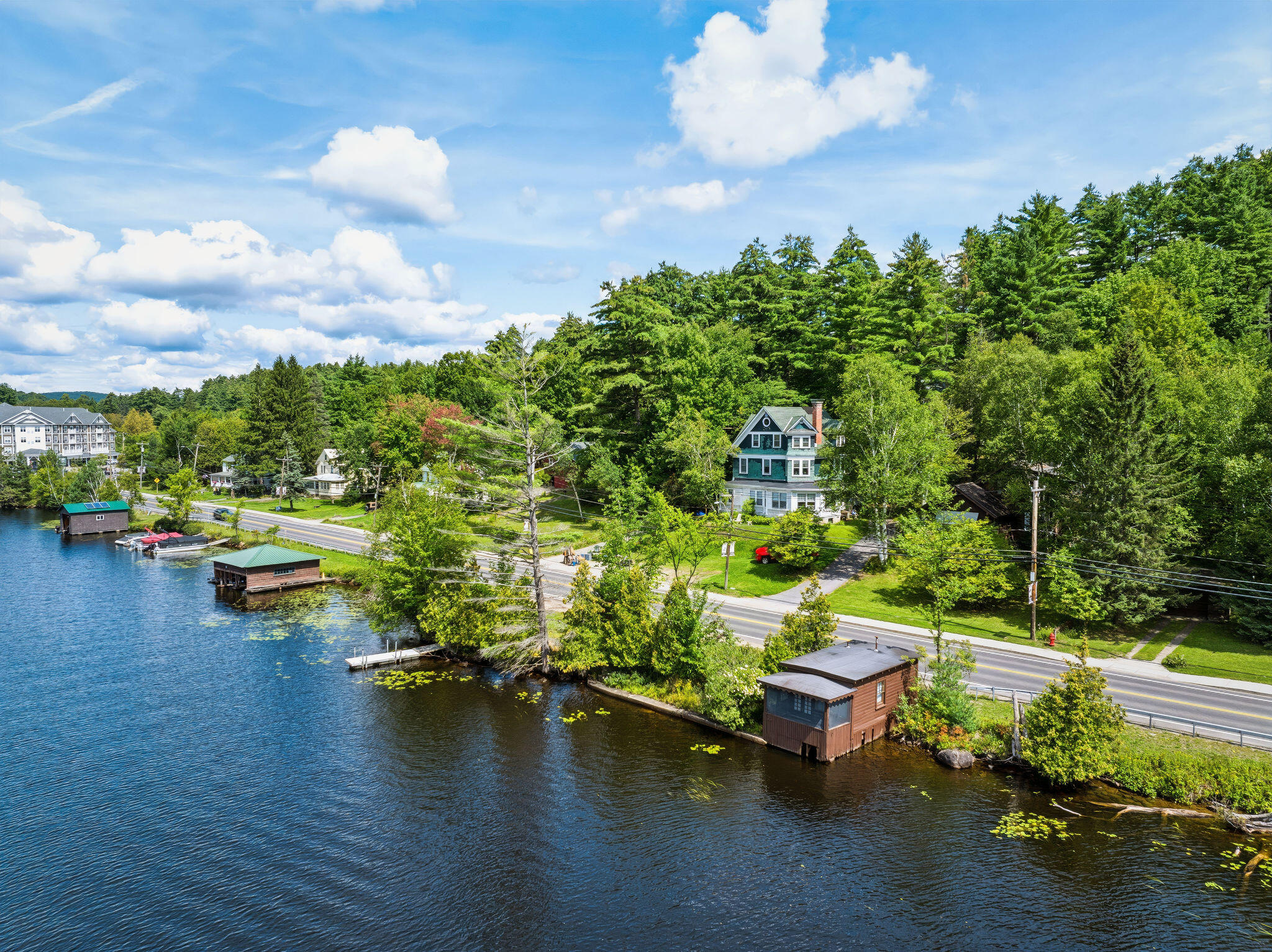 Aerial view of a lakeside house, with boathouses and docks along the wooded shoreline.