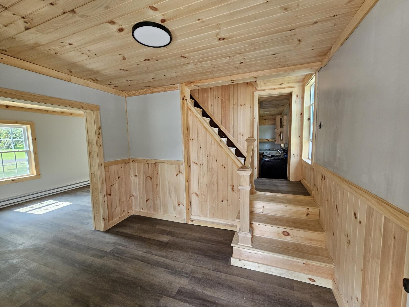 Wood-paneled staircase and hallway with a light pine ceiling and dark plank flooring.