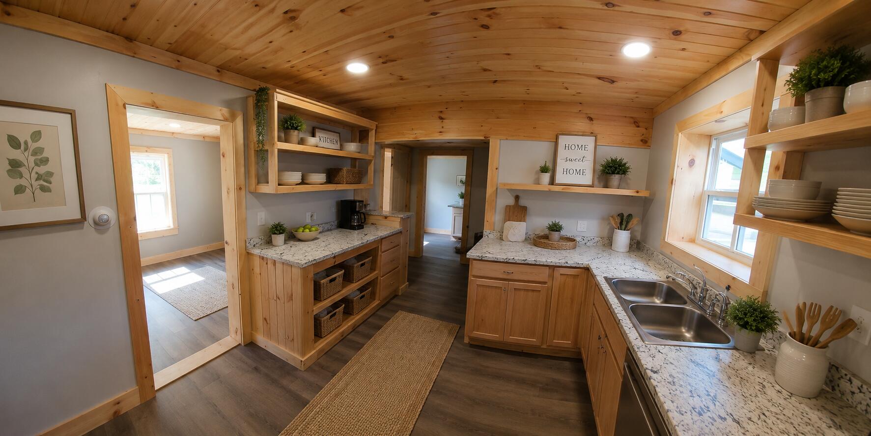 Kitchen with honey-colored wood cabinetry, open shelving, and a double-basin sink beneath a window.