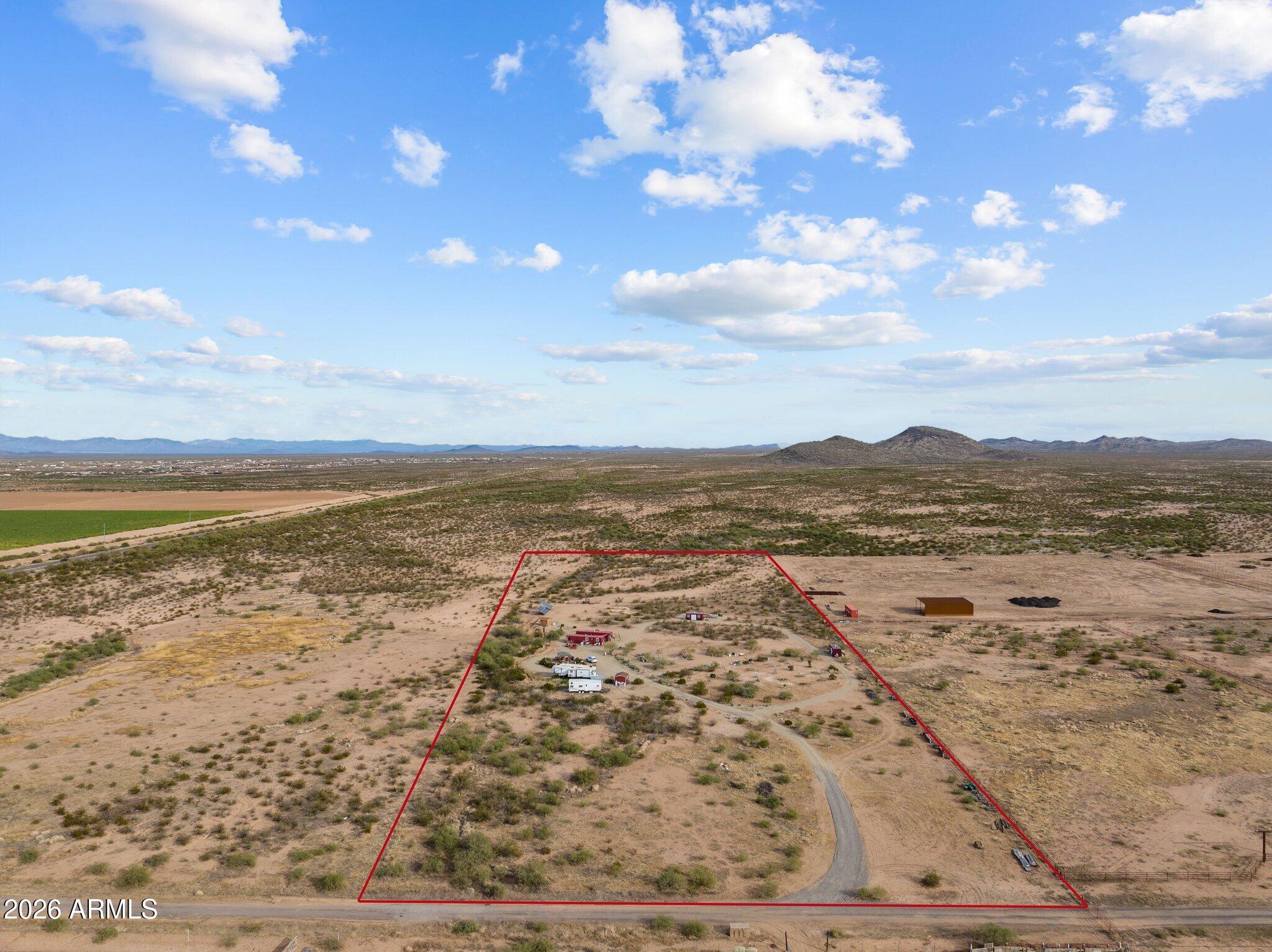 Aerial view of a red-outlined desert parcel with a curved access road and distant mountains.