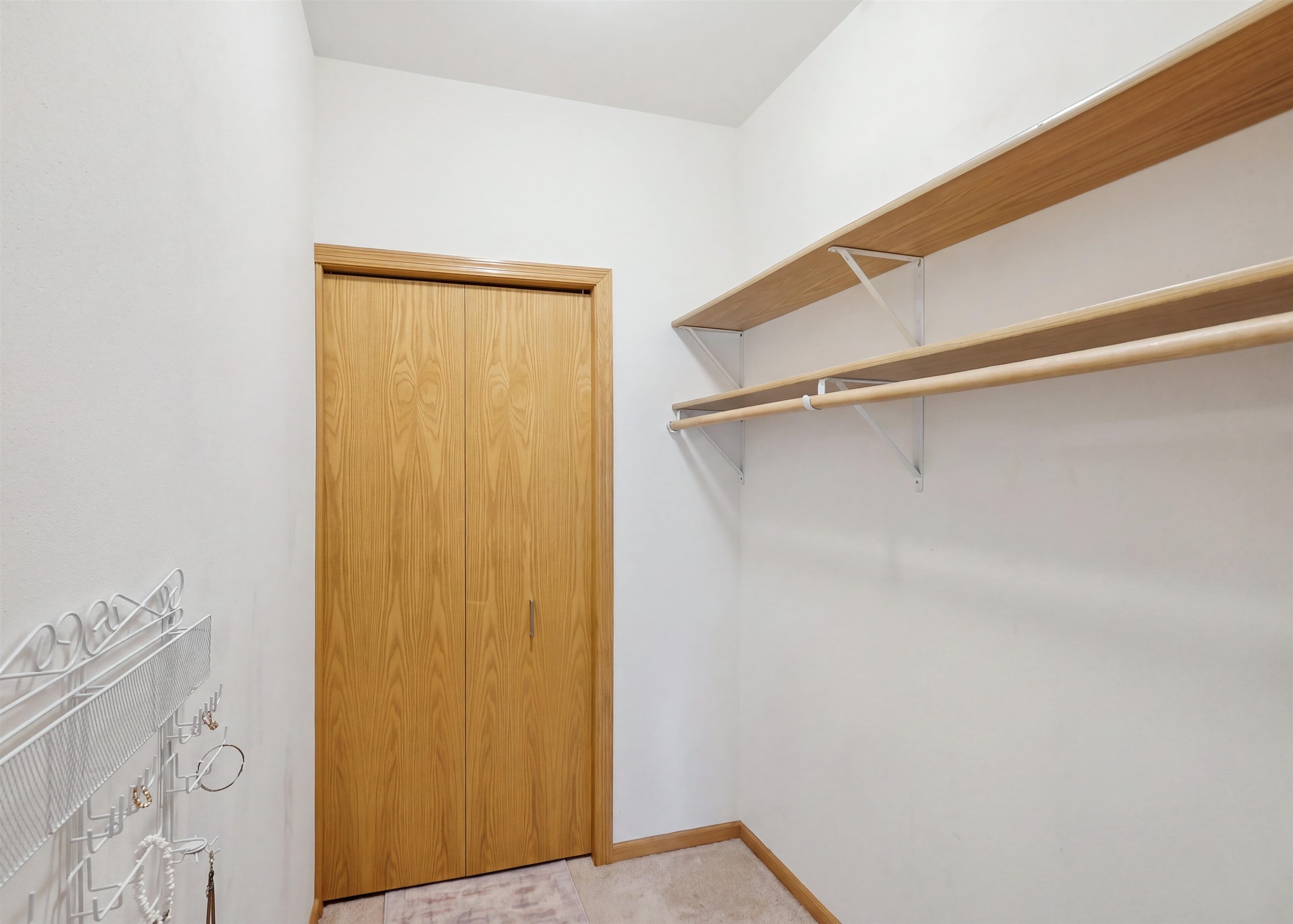 Walk-in closet with wooden cabinet doors, open shelves, hanging rods, and white wire organizers.