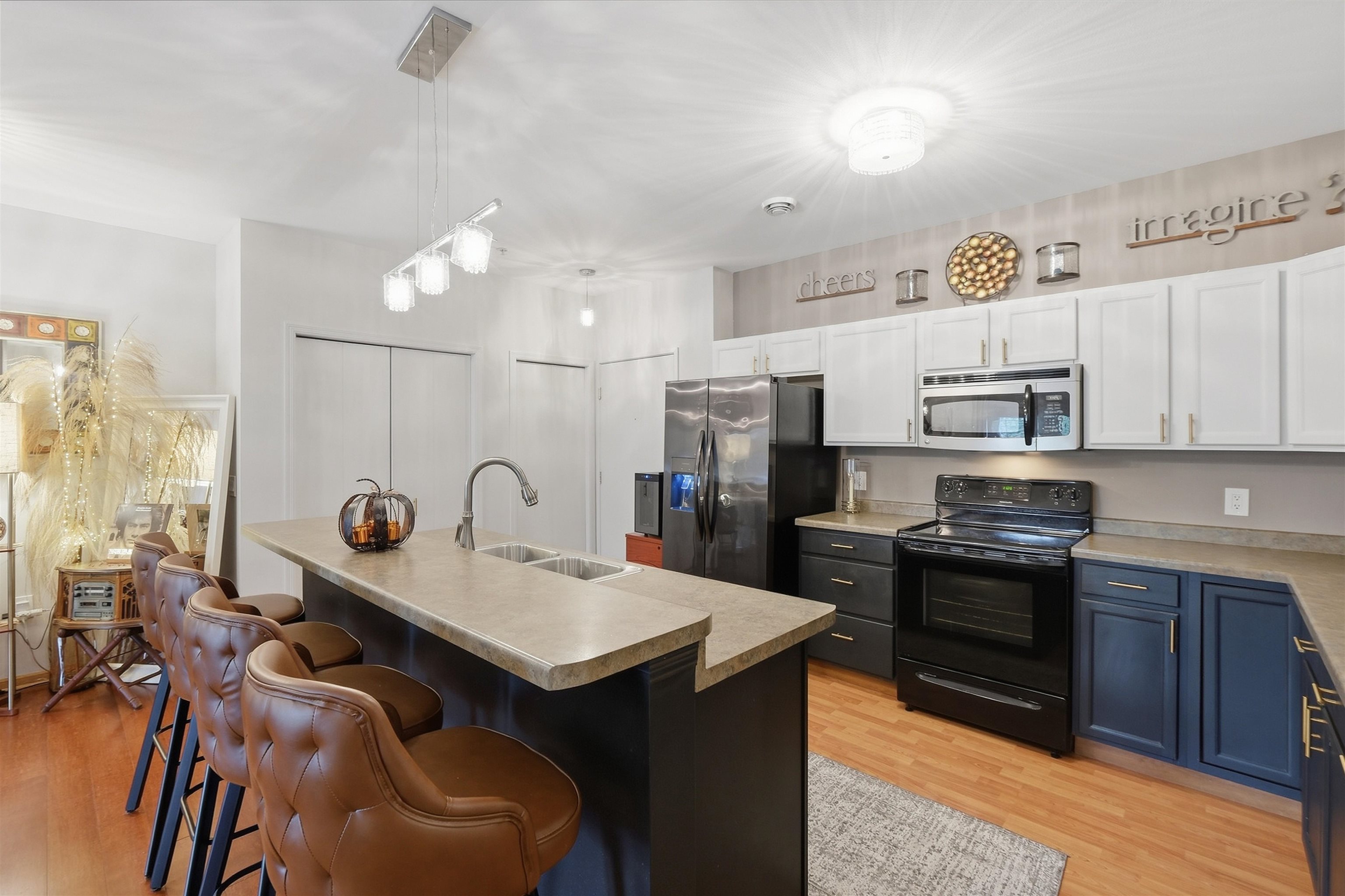 Kitchen with navy lower cabinets, stainless appliances, and a large island lined with leather bar stools.