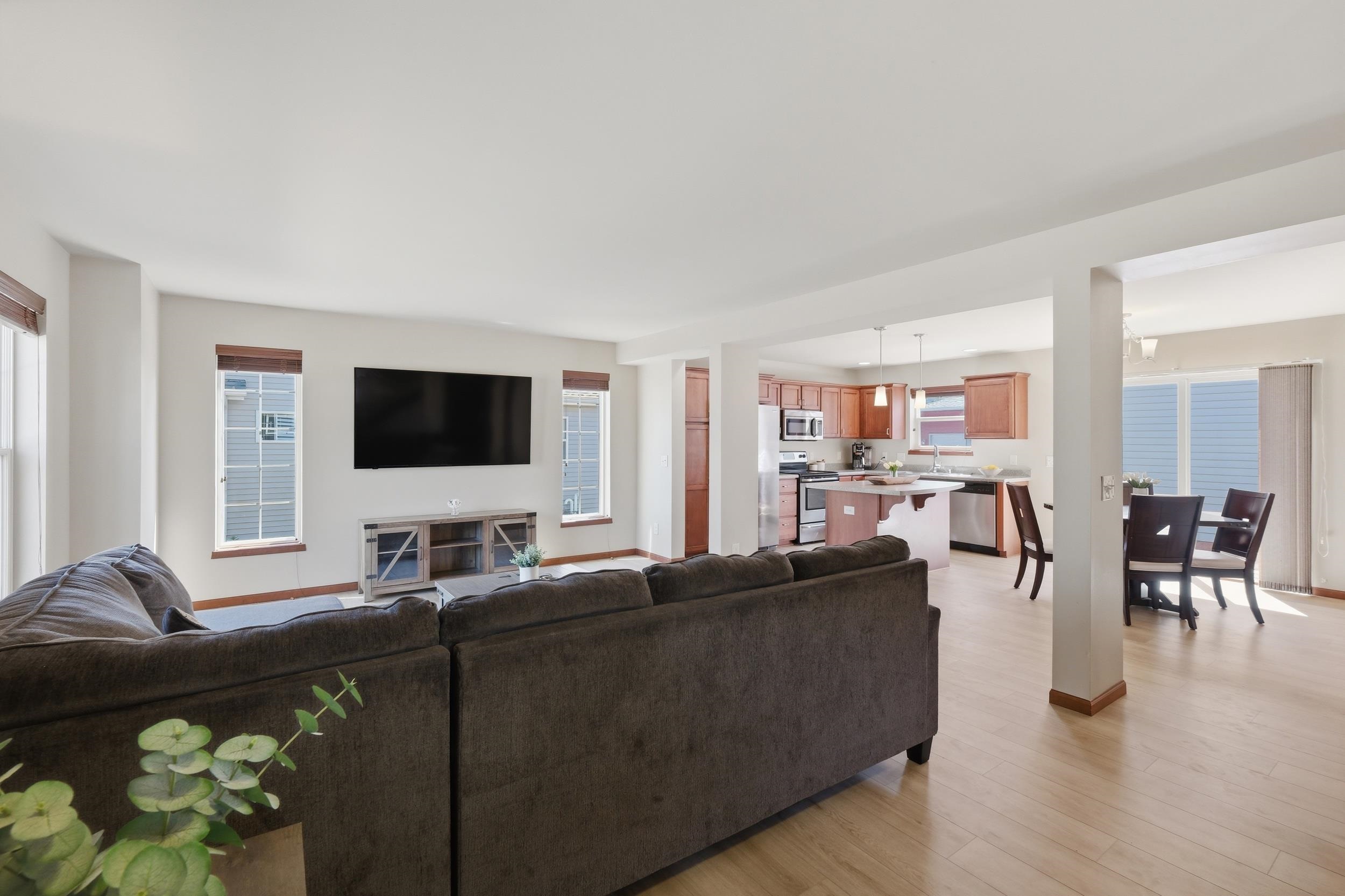 Open-plan living room with a dark sectional facing the kitchen island and dining area.