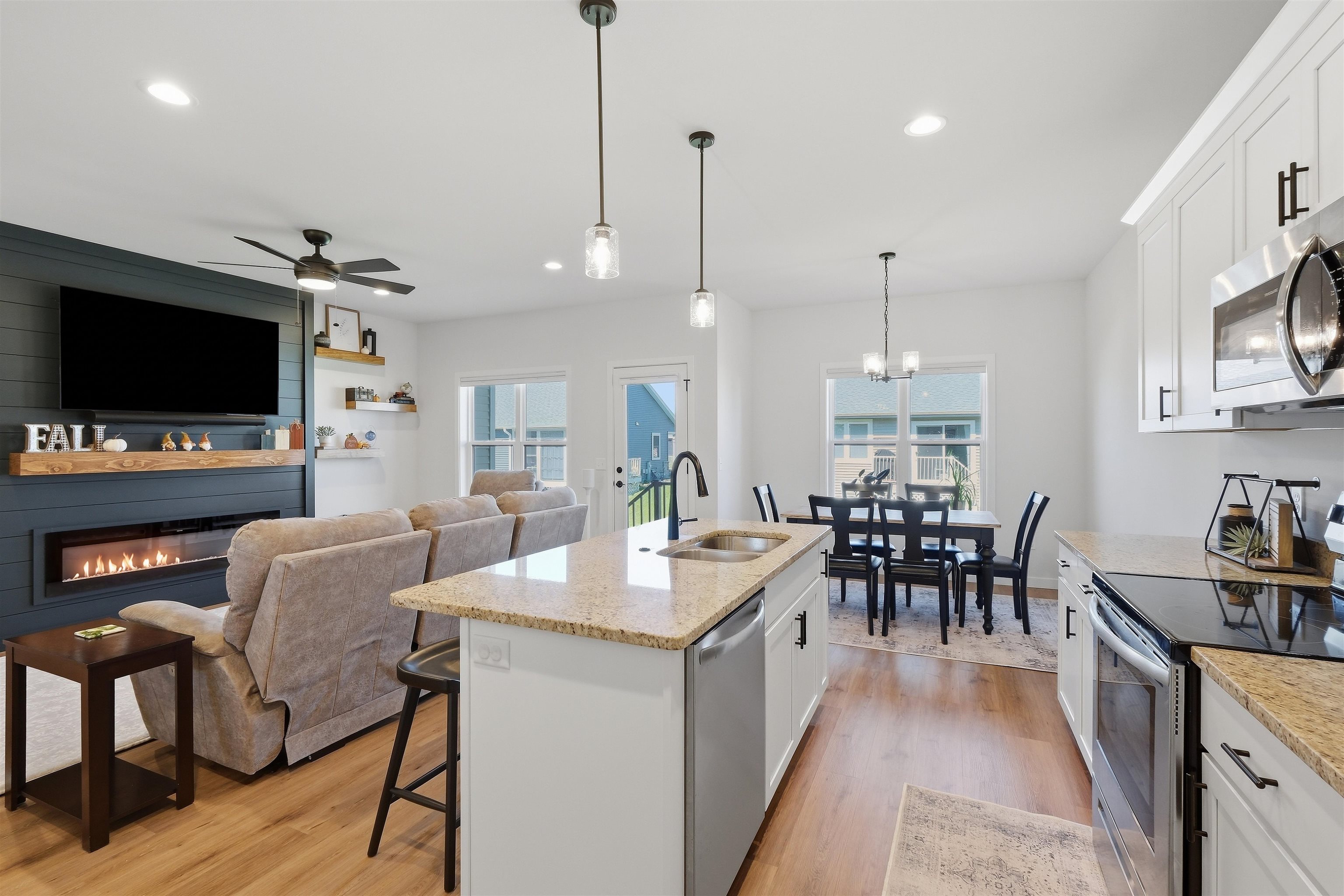 Open-plan kitchen with granite island, white cabinets, dining area, and living room fireplace.