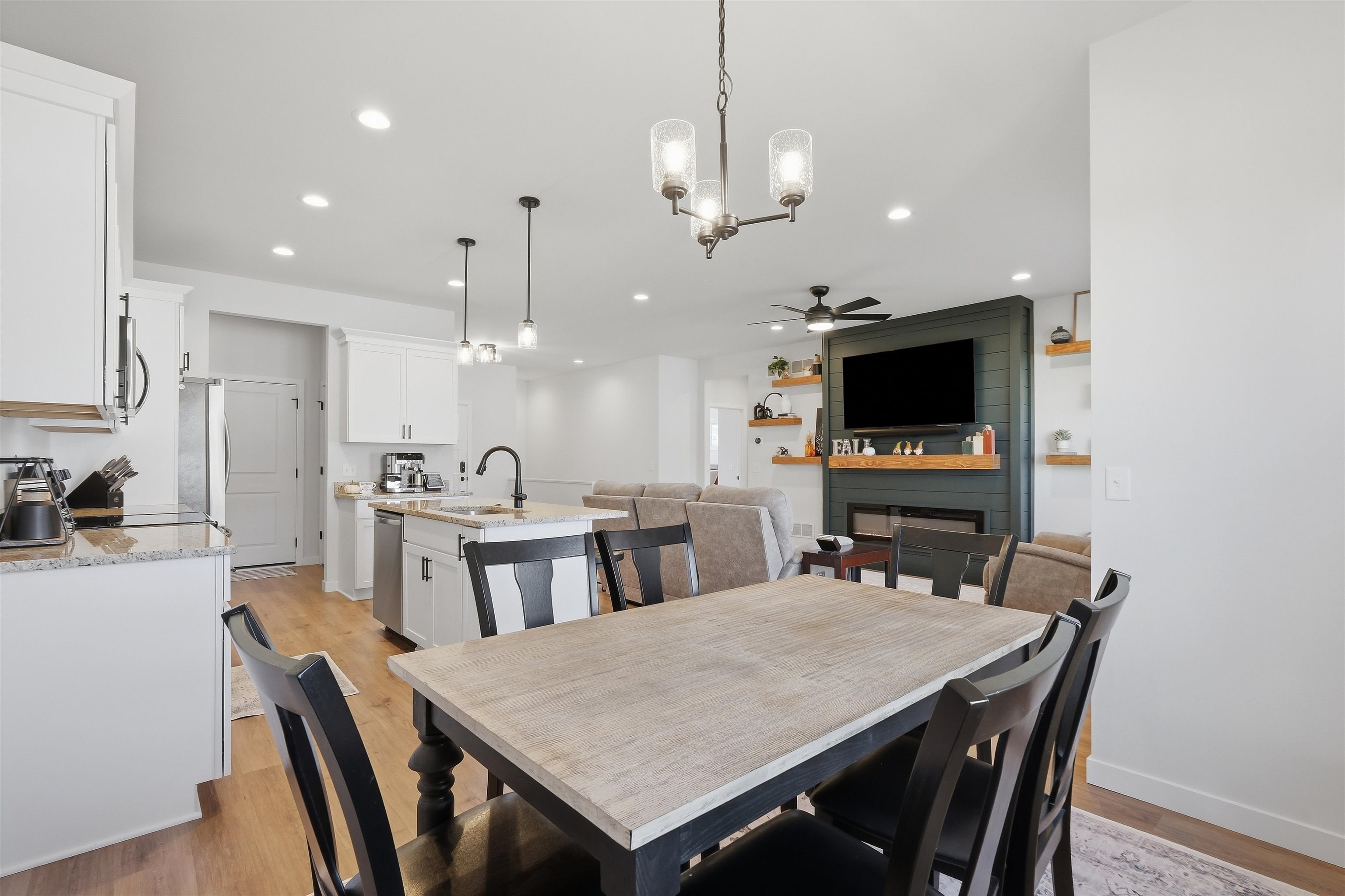 Open-plan kitchen and dining area with a granite island and dark fireplace wall.