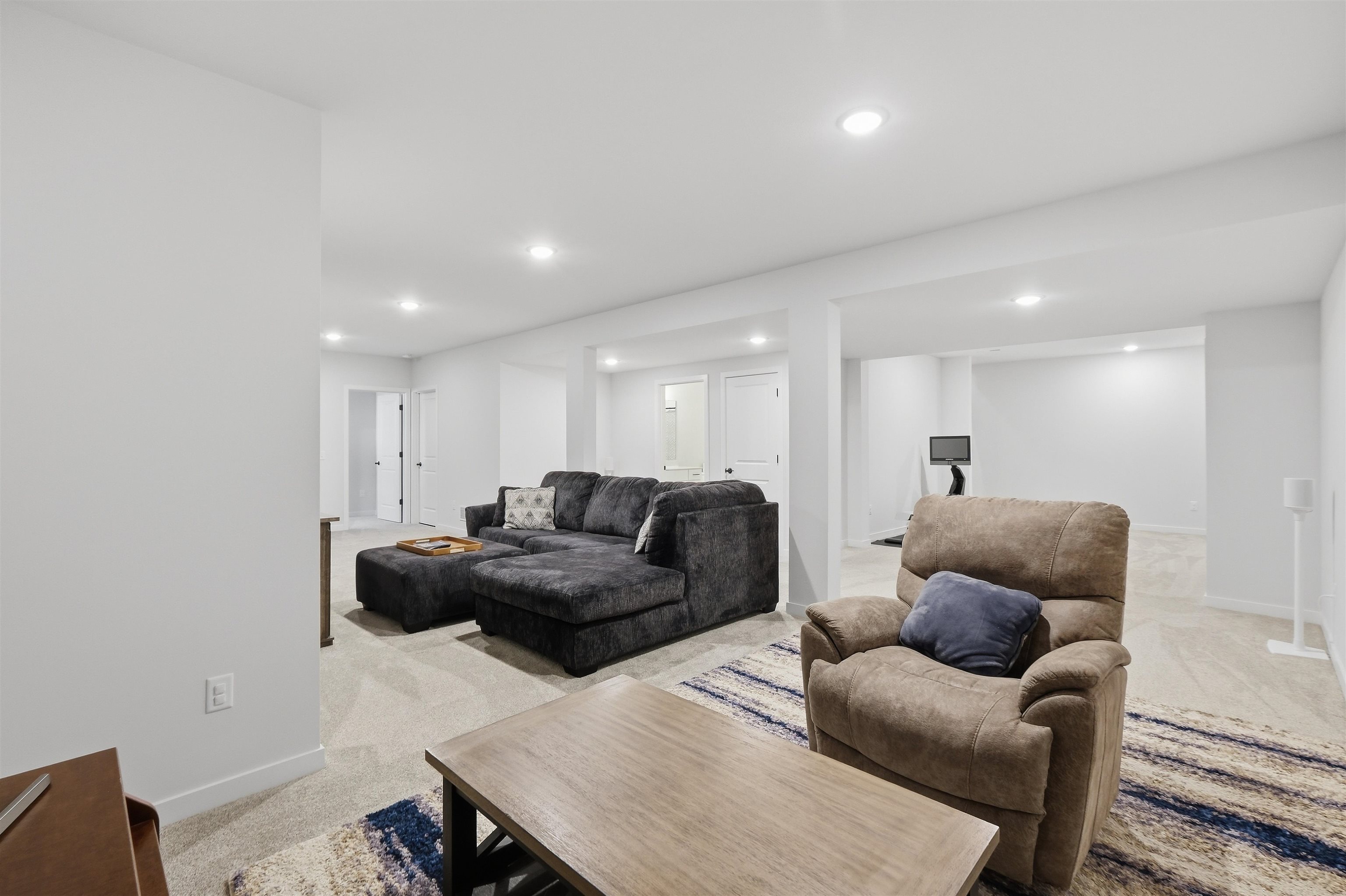 Furnished living area with a dark sectional, tan recliner, and patterned rug.