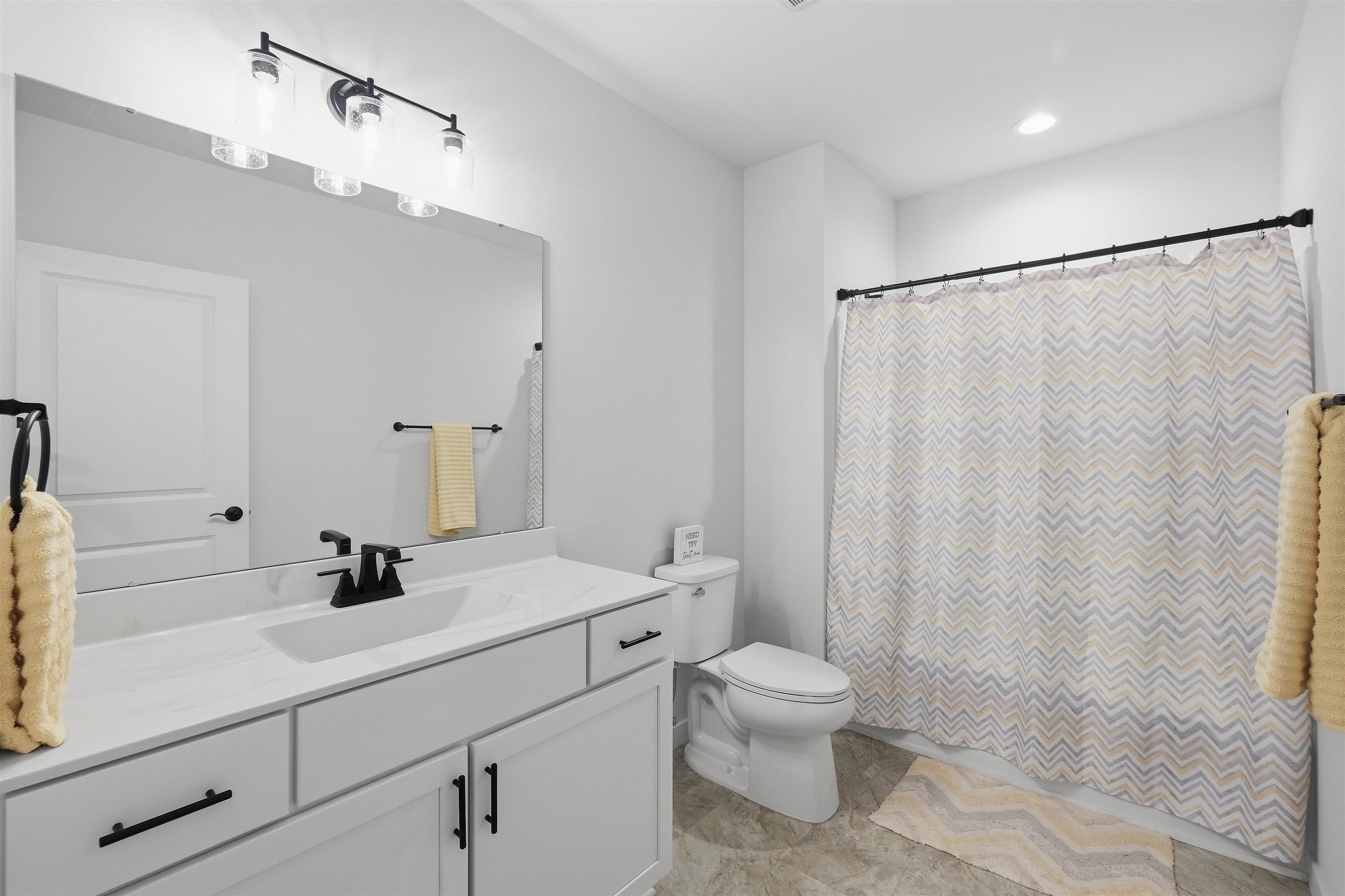 Bathroom with a white vanity, black fixtures, and a chevron shower curtain.