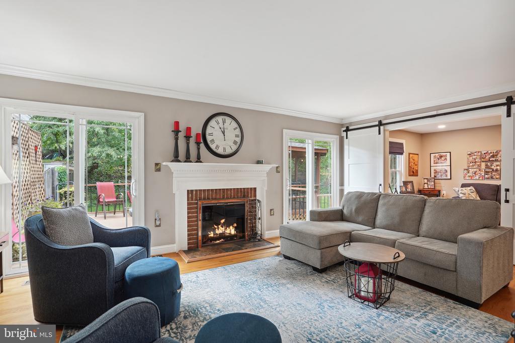 Living room with brick fireplace, gray sectional, and glass doors opening to patio.