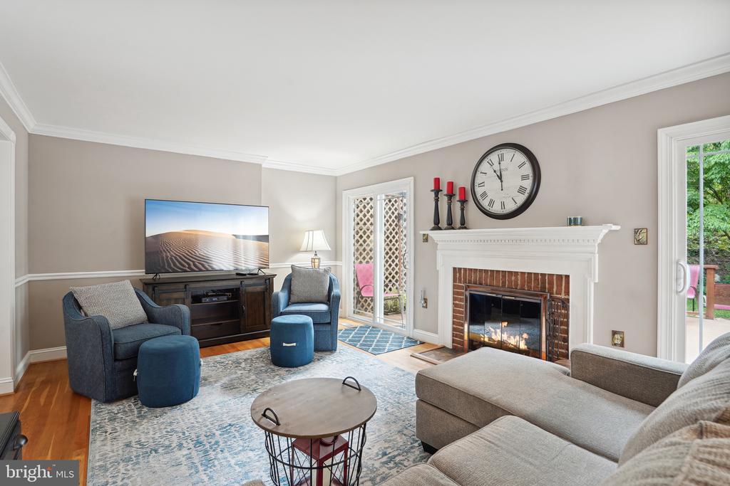Living room with a brick fireplace, blue armchairs, gray sectional, and glass doors to a patio.