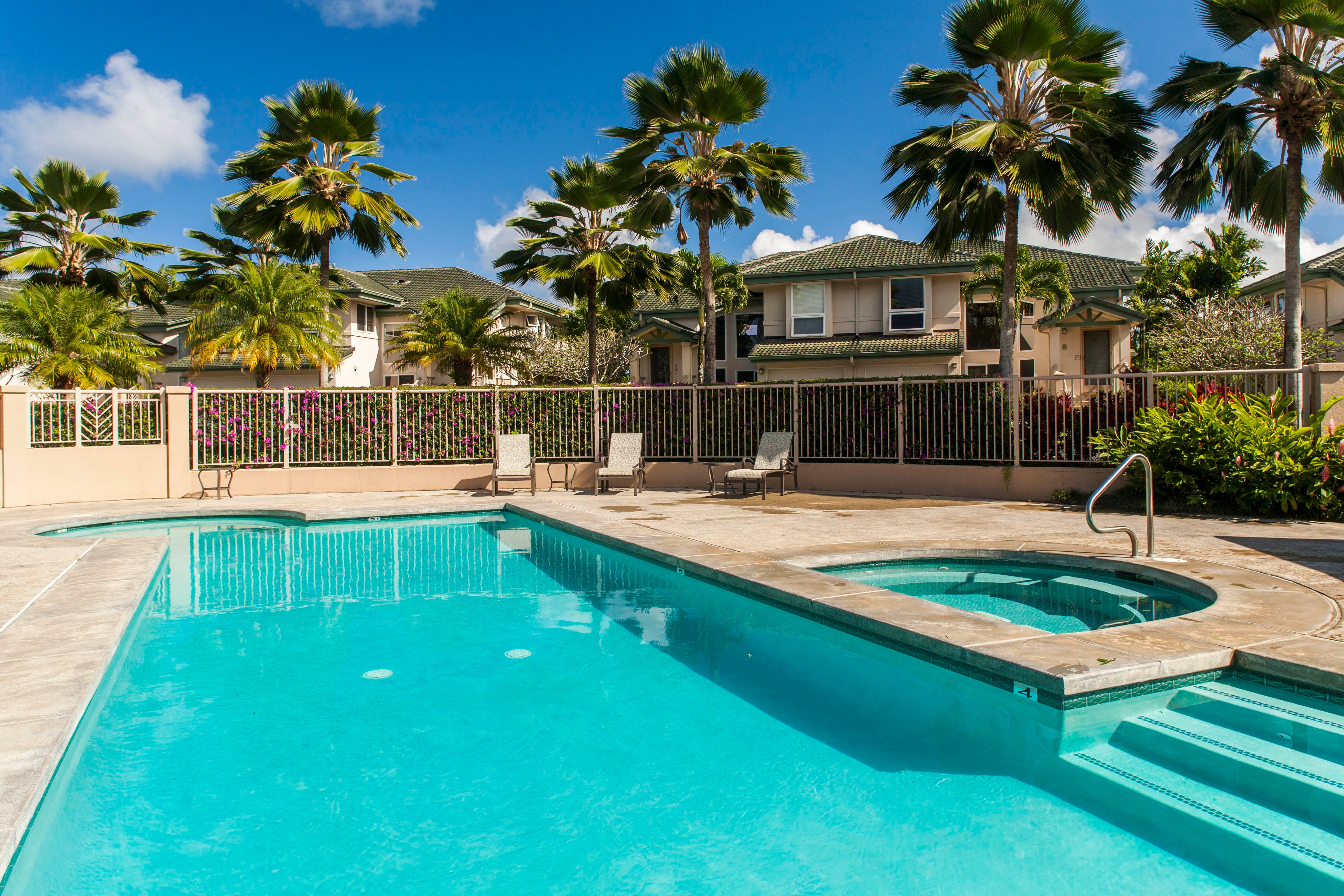 Outdoor pool and spa framed by palm trees and condominium buildings.