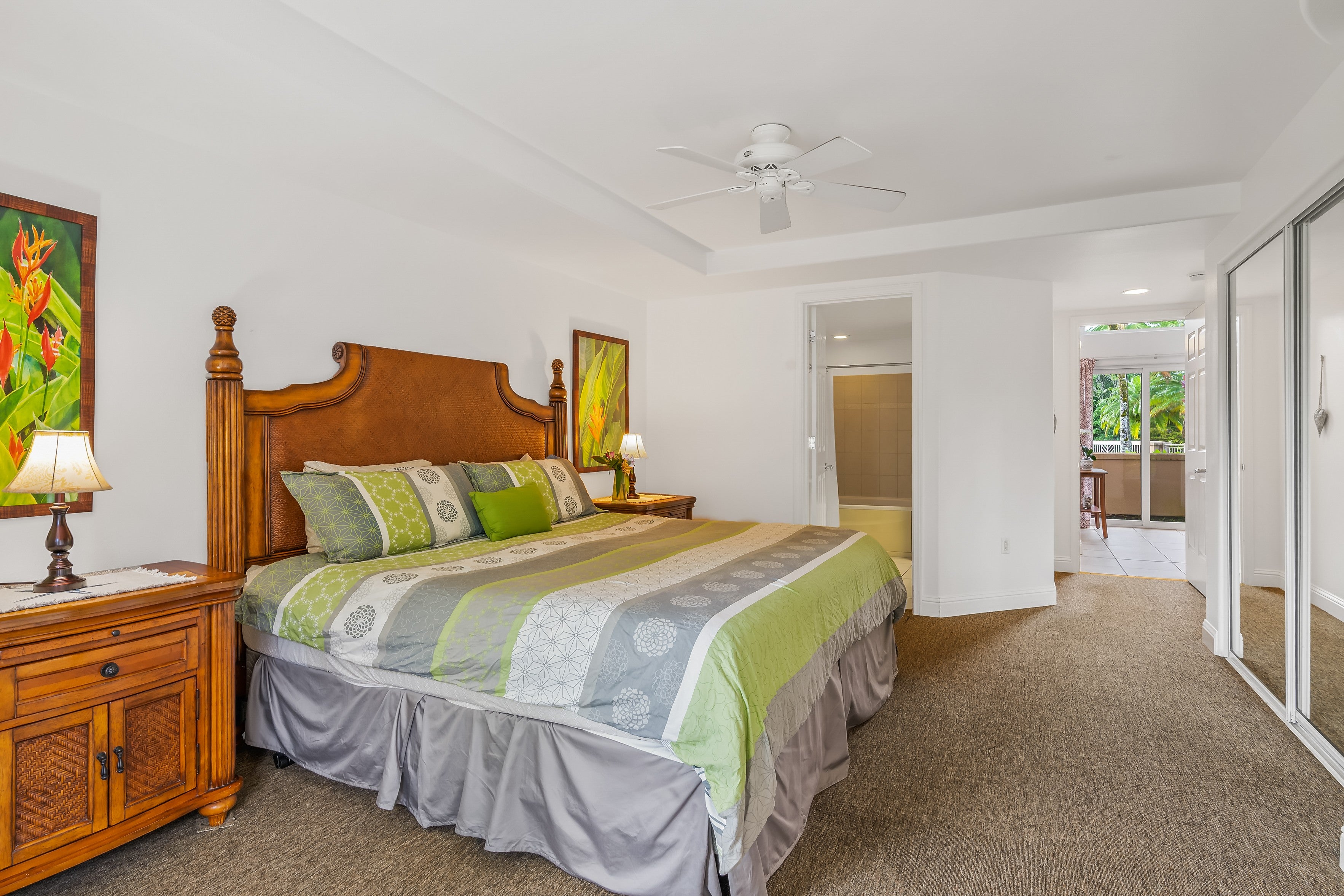 Bedroom with a carved wooden four-poster bed, green patterned bedding, and sliding glass doors.
