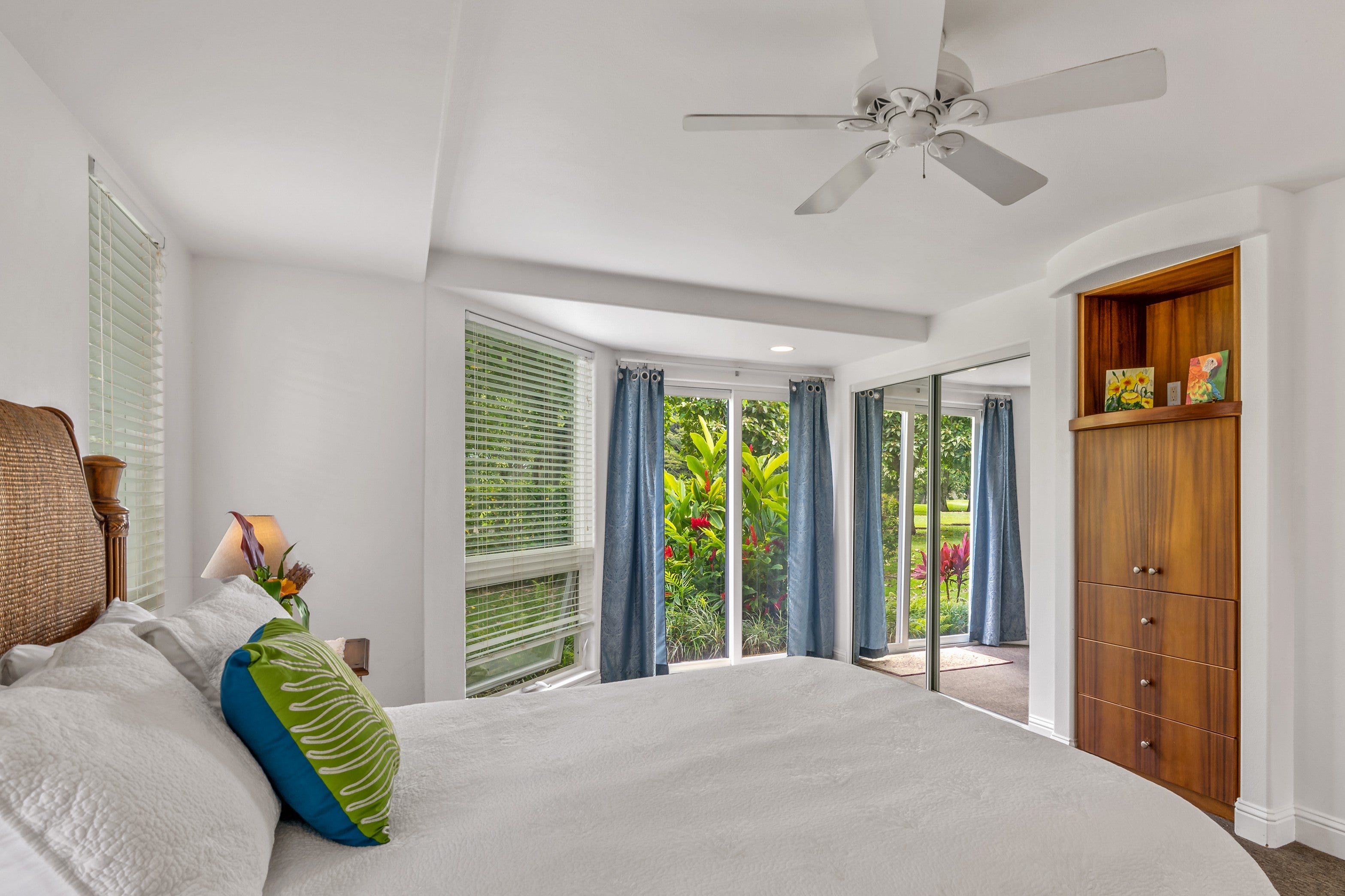 Bedroom with a ceiling fan, built-in wooden cabinets, and garden-facing sliding glass doors.