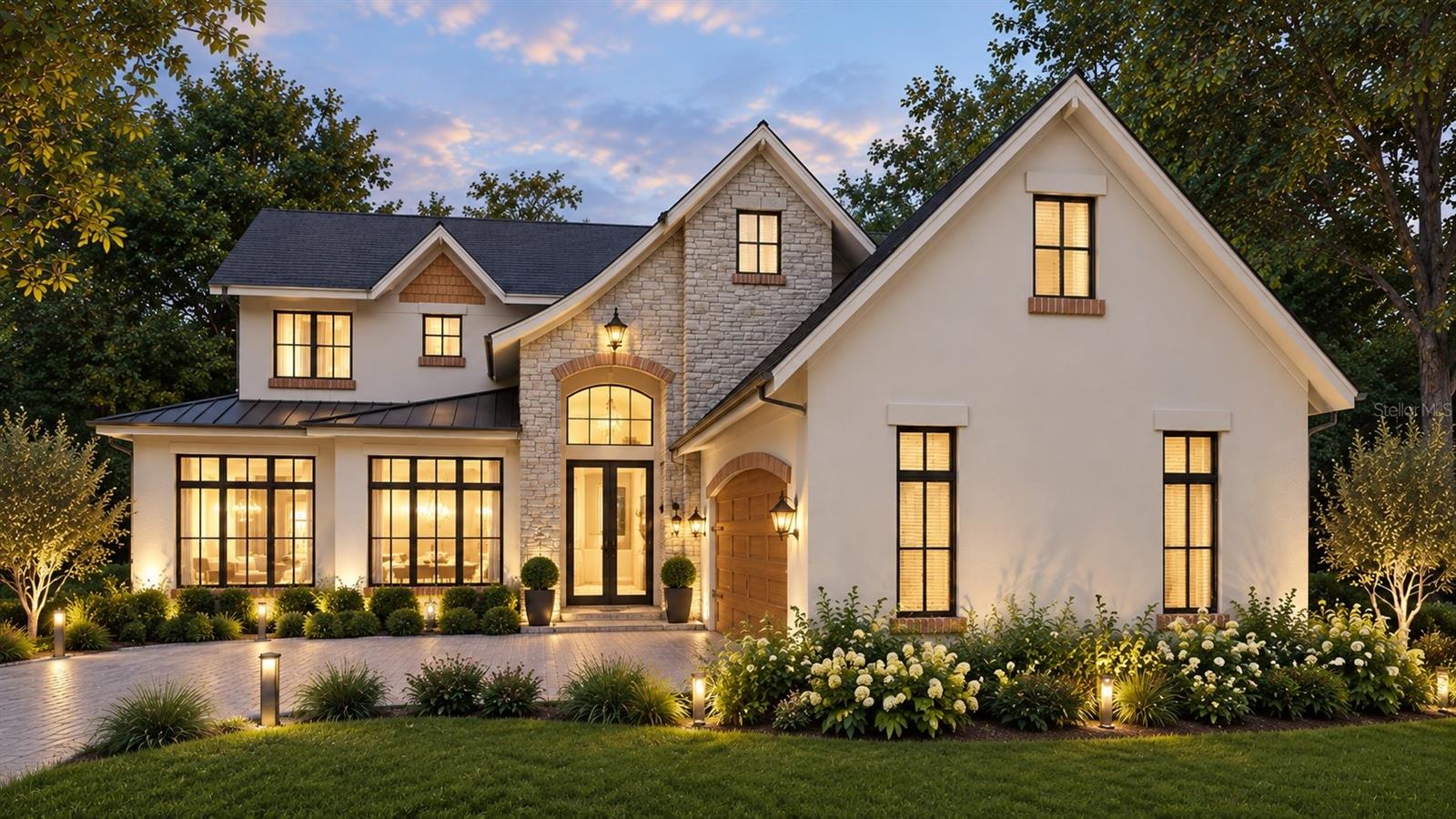 Two-story stucco and stone home with a steep gabled roof, arched entry, and warmly lit windows at dusk.