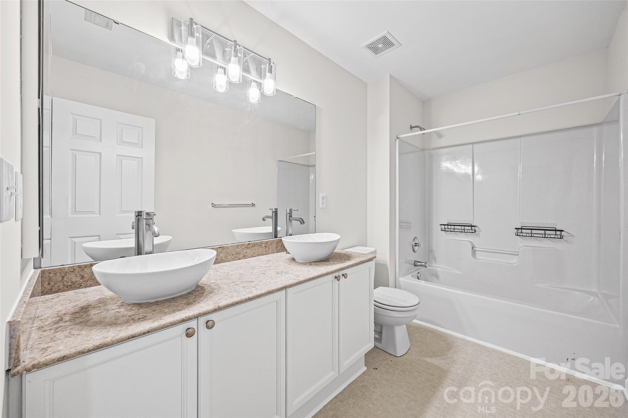Bathroom with double vessel sinks and a large mirror beside a tub and shower.
