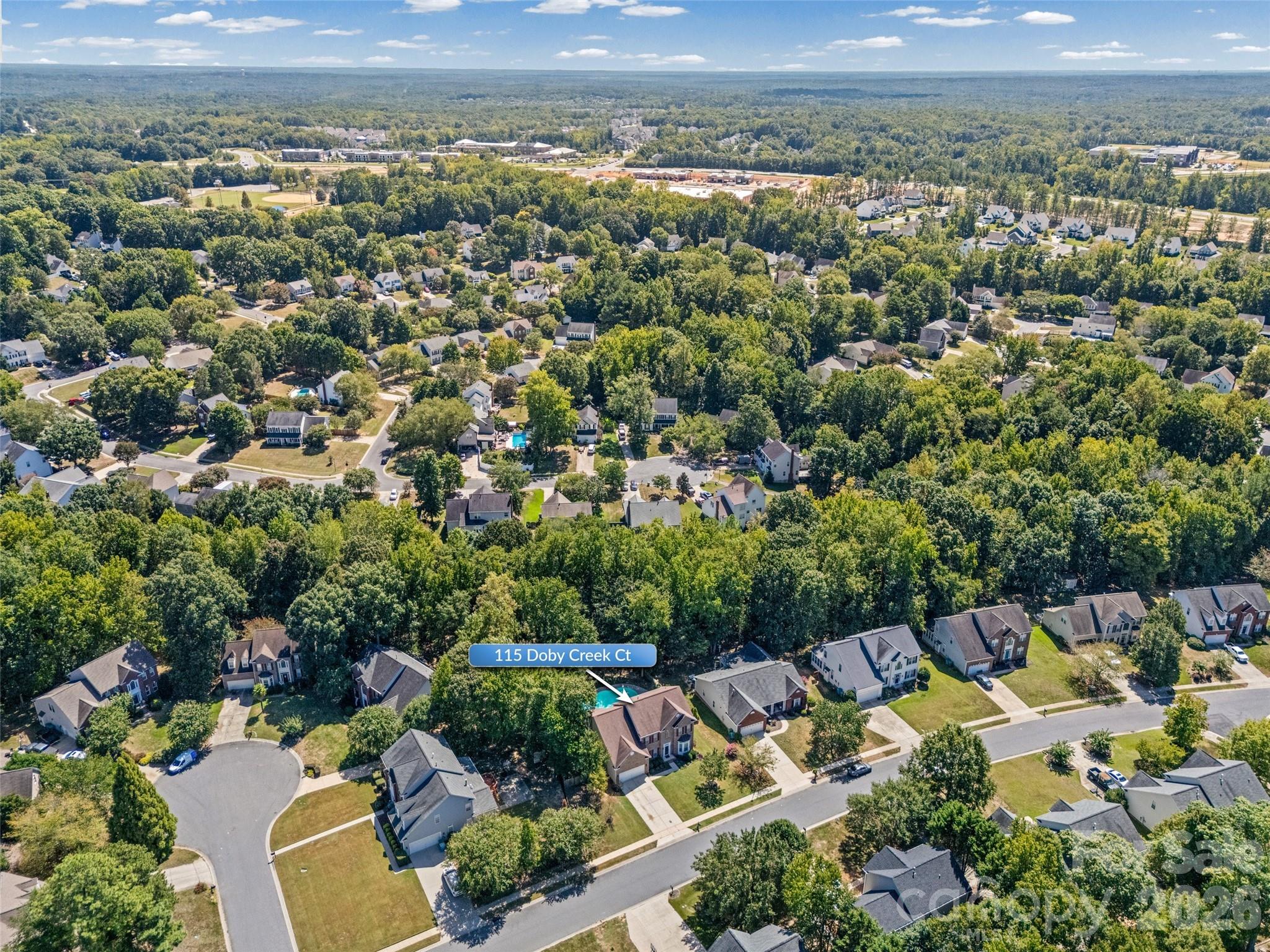 Aerial view of 115 Doby Creek Ct, marked by an arrow among tree-lined homes.