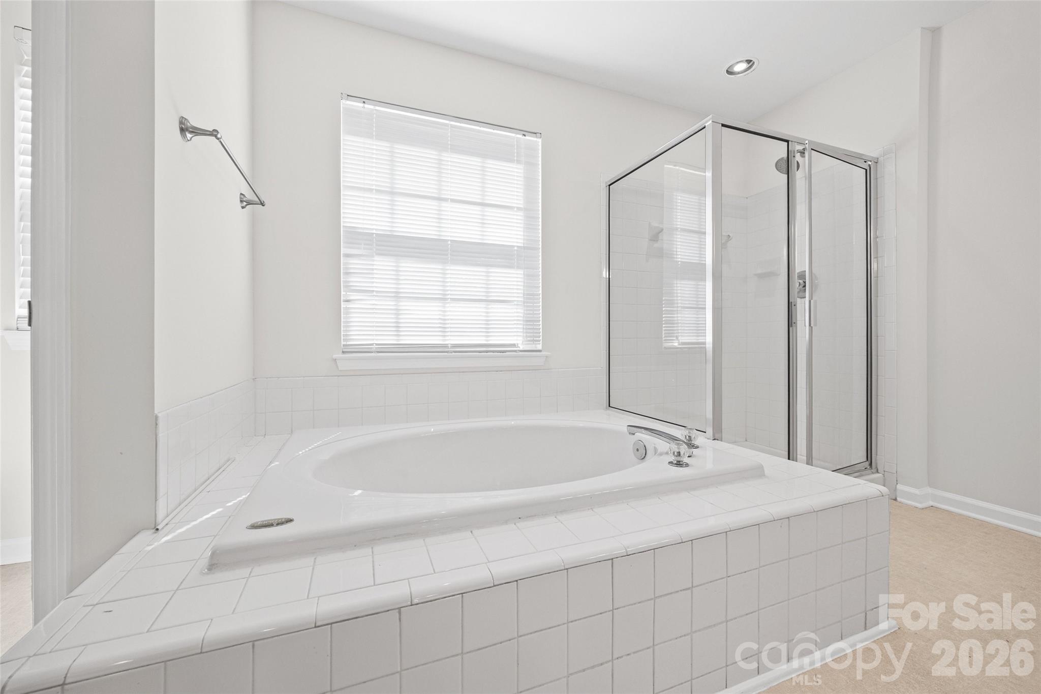 Bathroom with a large tiled corner soaking tub and glass-enclosed shower.