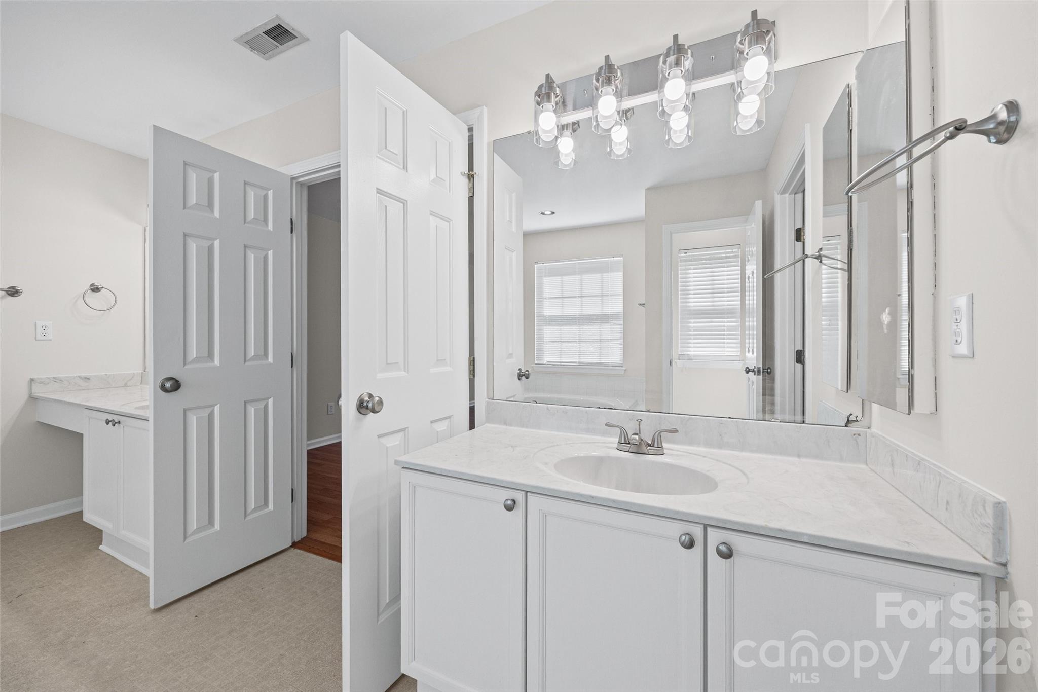 Bathroom with a marble-look vanity, oval sink, large mirror, and chrome light fixtures.