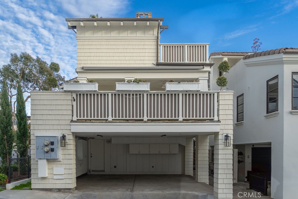 Two-story home with a broad white-railed balcony above a covered carport.