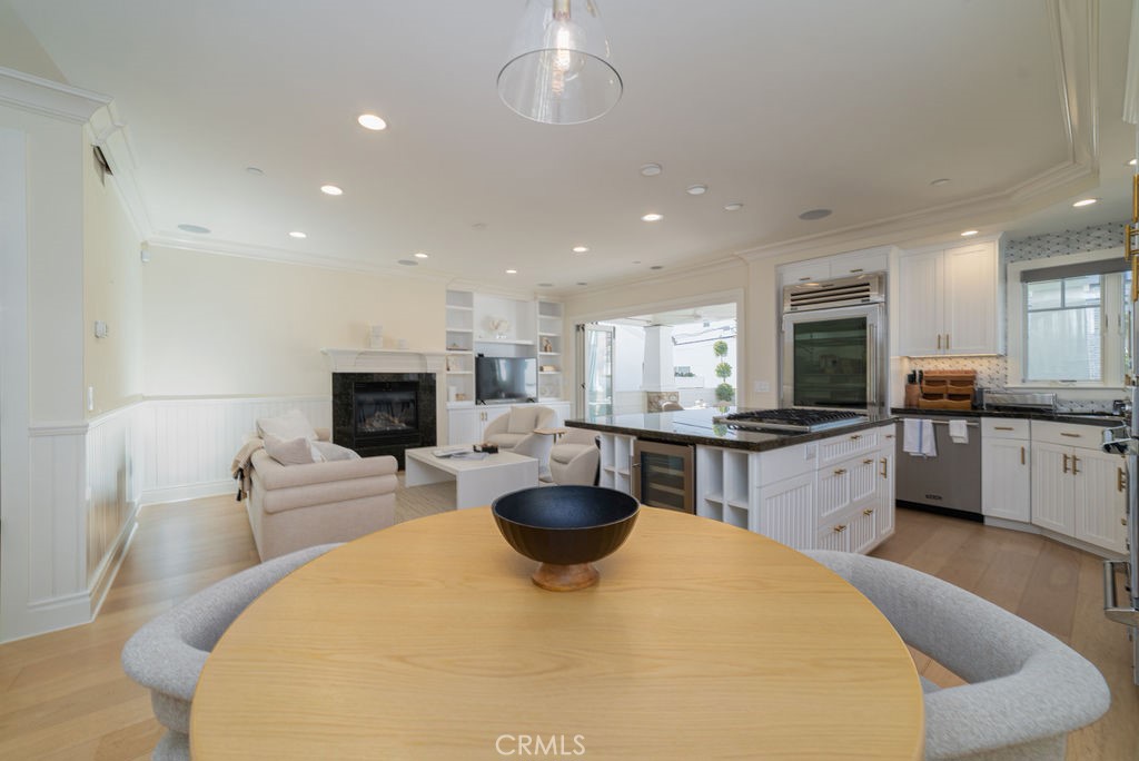 Open-plan kitchen and living area with a large island, white cabinetry, and round dining table.