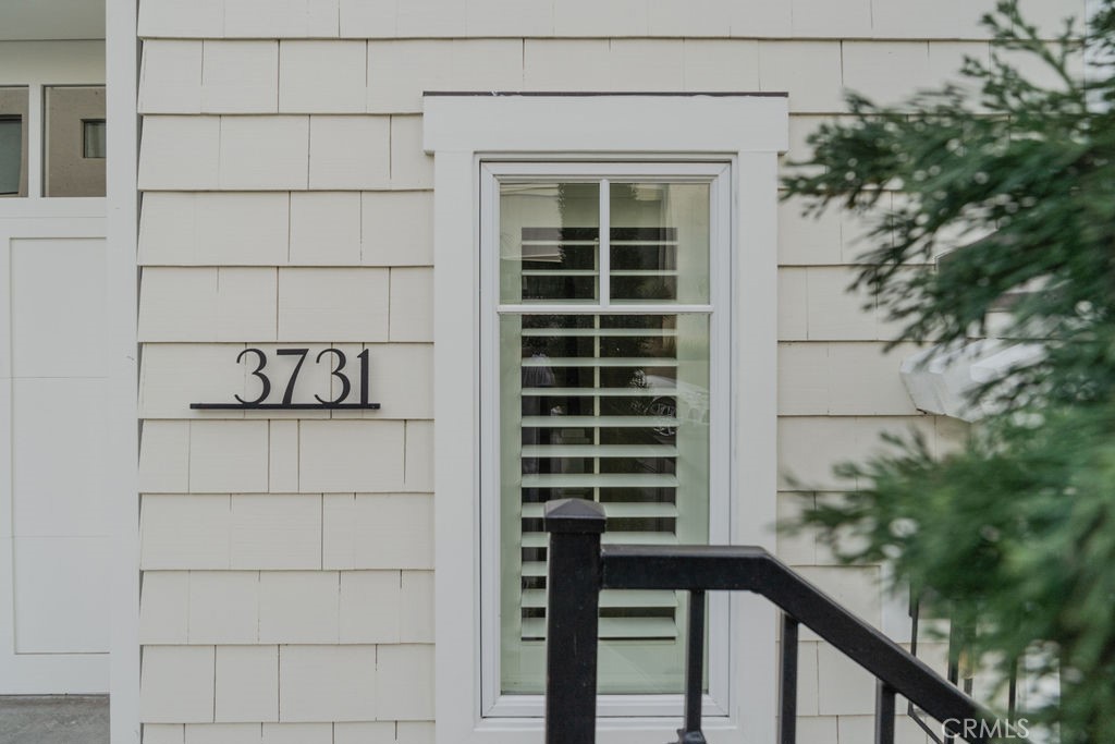Home exterior with the number 3731 beside a shuttered window and dark entry railing.