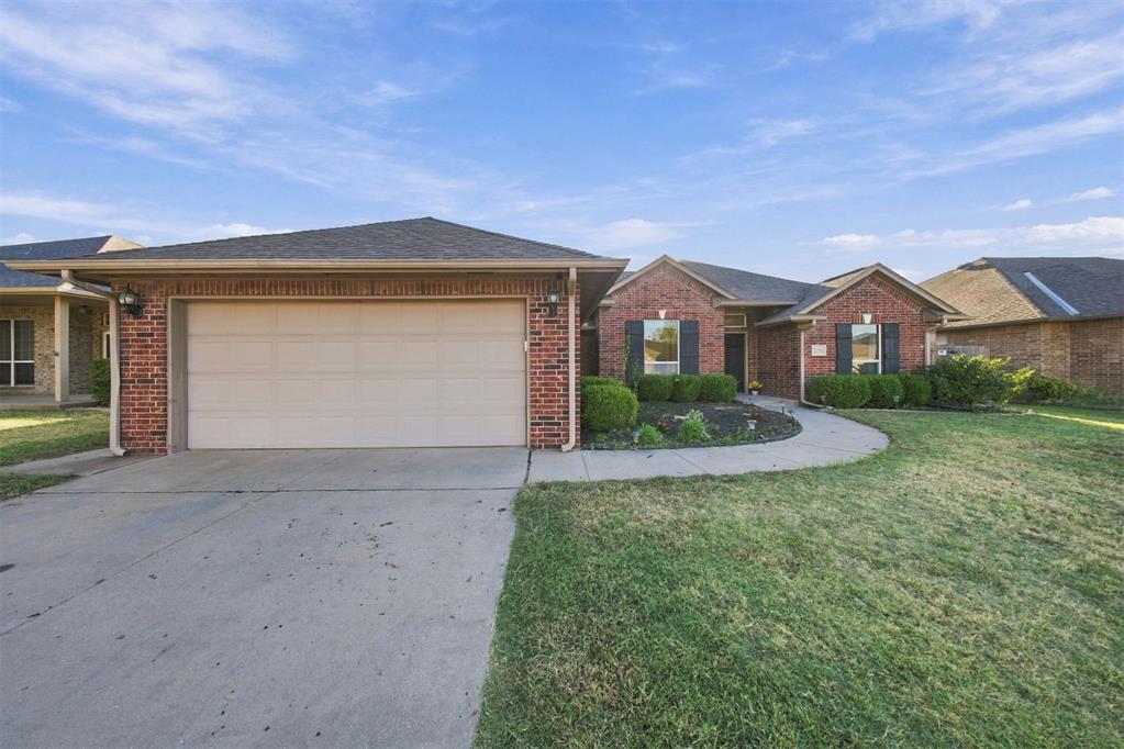 Brick home with a two-car garage and curved walkway across the front lawn.