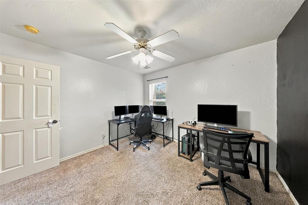 Home office with multiple computer monitors, two desks, and a ceiling fan.