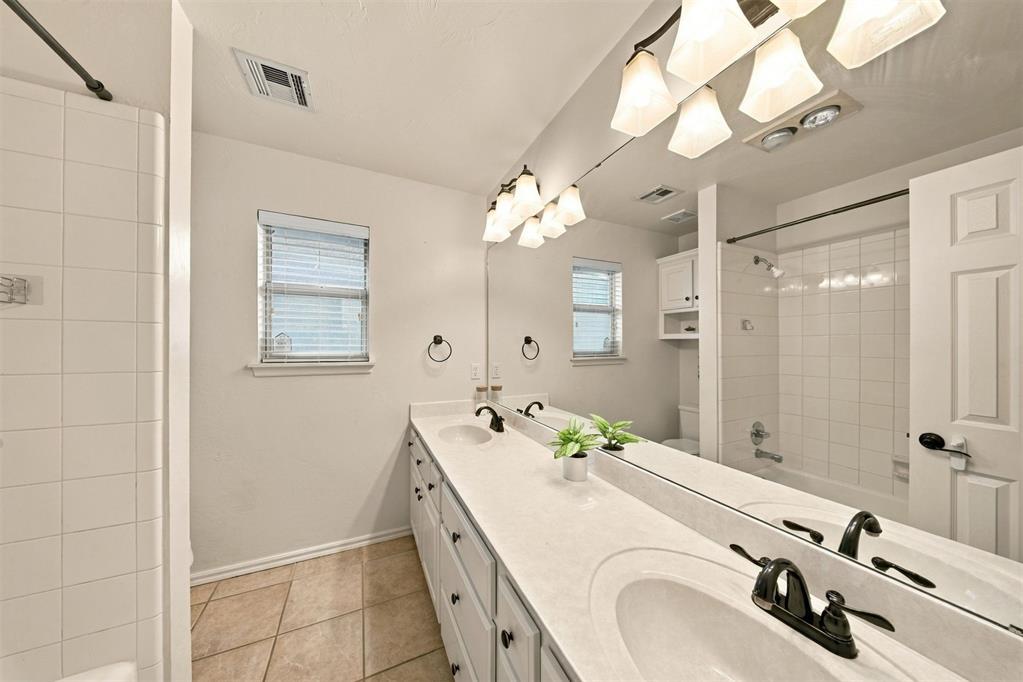 Bathroom with a long double vanity, large mirror, and tiled tub and shower.