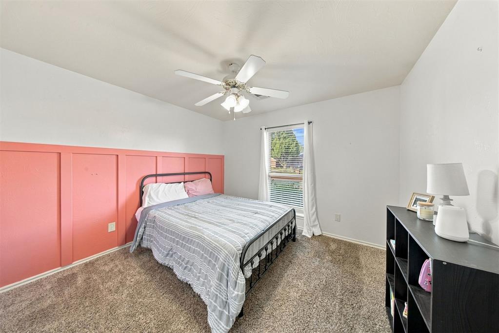 Bedroom with a black metal bed, gray striped bedding, and coral paneled accent wall.