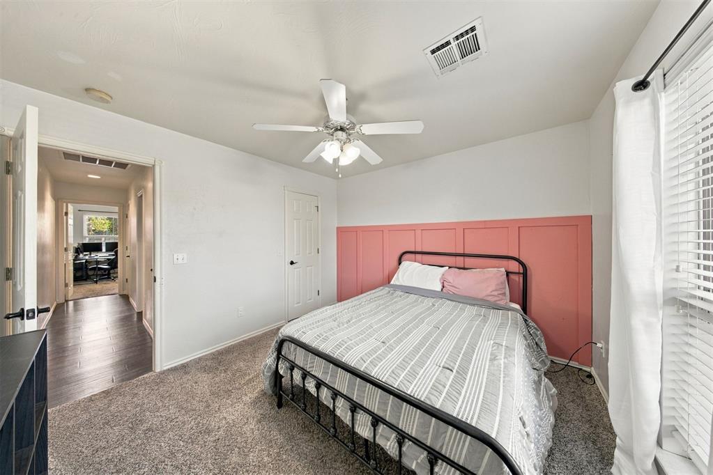 Bedroom with a black metal bed, gray striped bedding, and coral paneled accent wall.