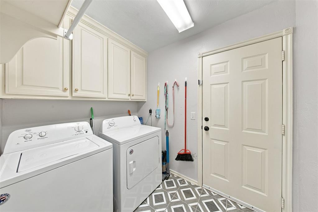 Laundry room with a washer and dryer, built-in cabinets, and geometric tile flooring.