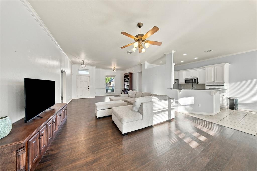 Living room with a large sectional sofa, ceiling fan, and open kitchen.