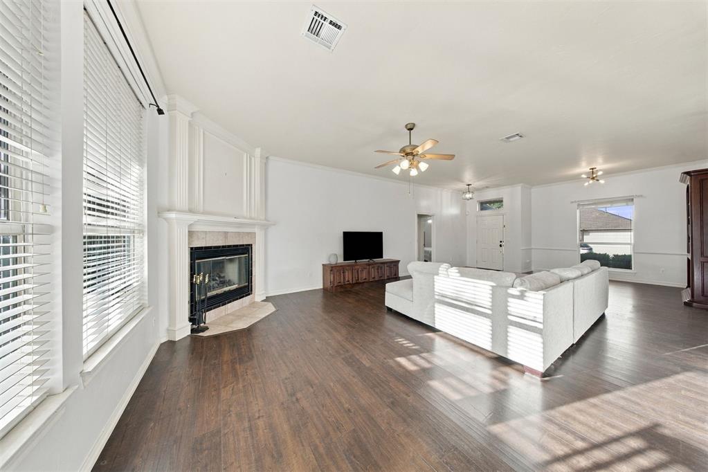 Living room with a white sectional, white-mantel fireplace, dark wood floors, and large windows.