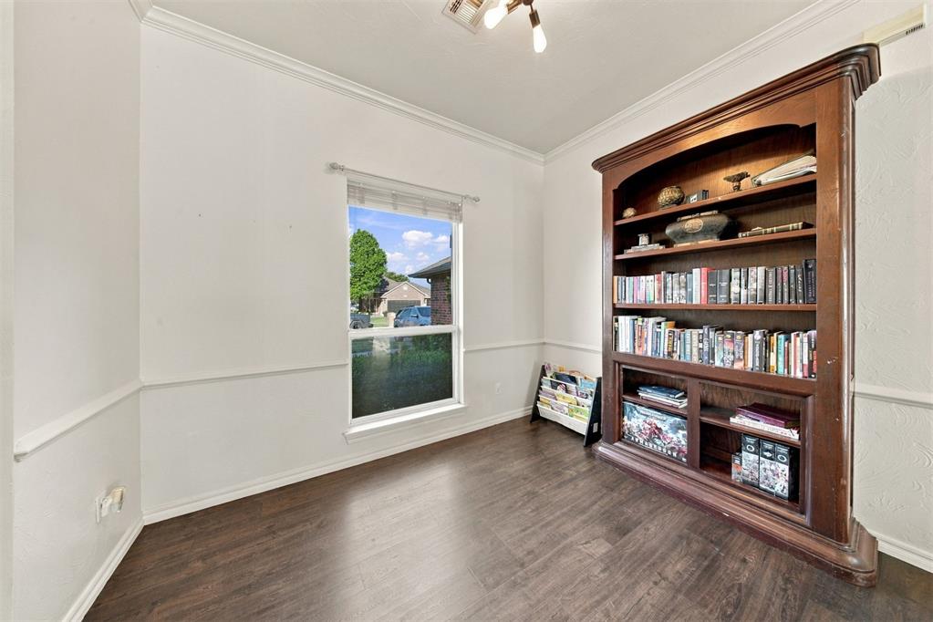 Empty room with dark wood floors and a built-in bookcase filled with books.