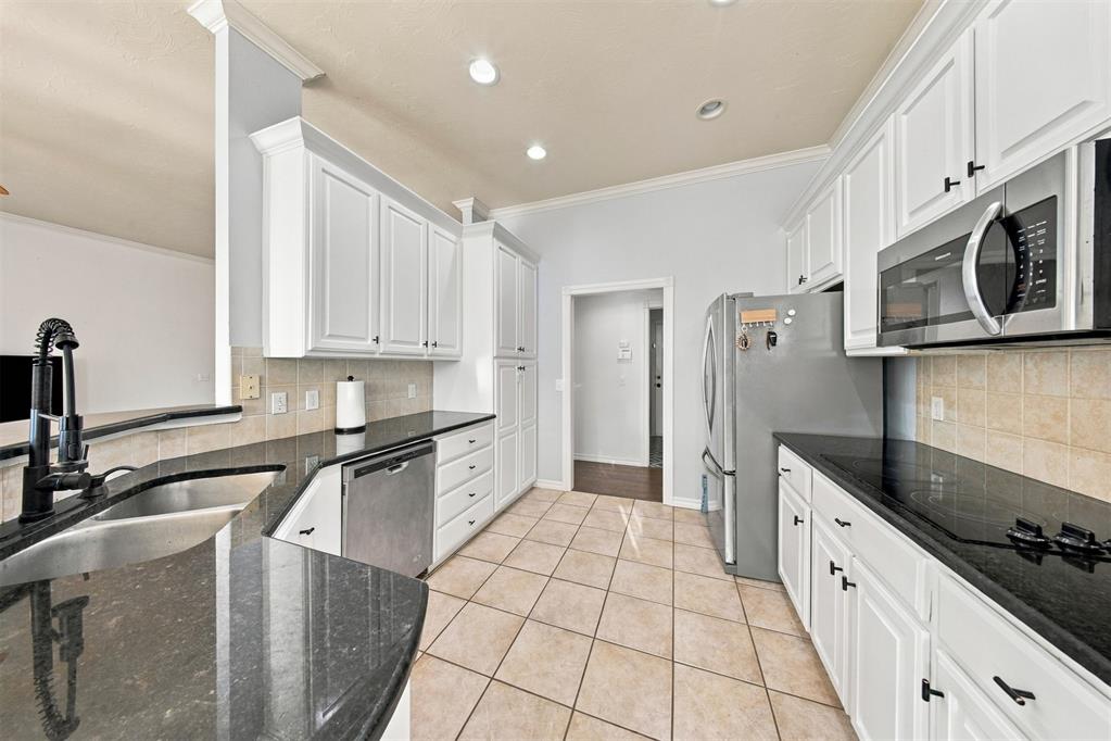 Kitchen with white cabinets, black granite counters, and stainless steel appliances.
