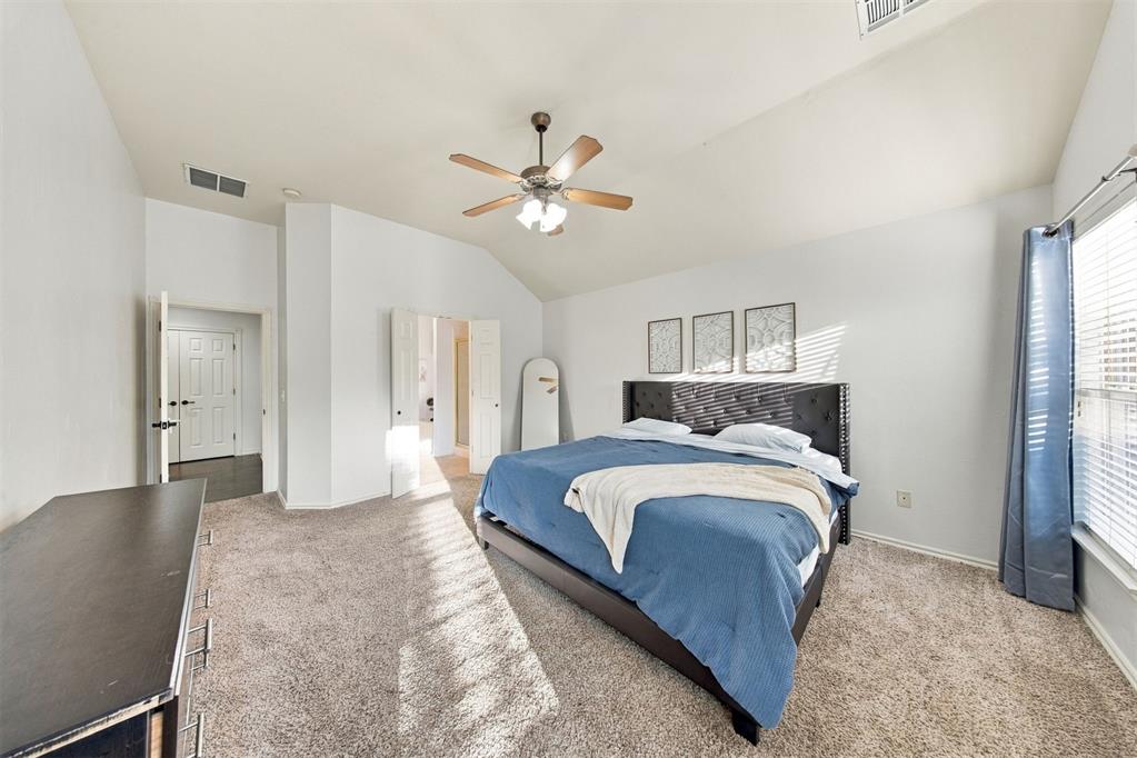 Bedroom with a blue-covered bed, vaulted ceiling, and ceiling fan.