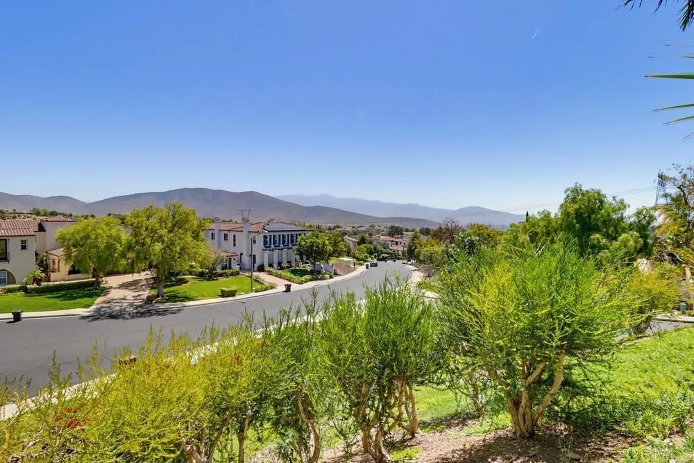 Residential street with landscaped homes and distant mountain views.