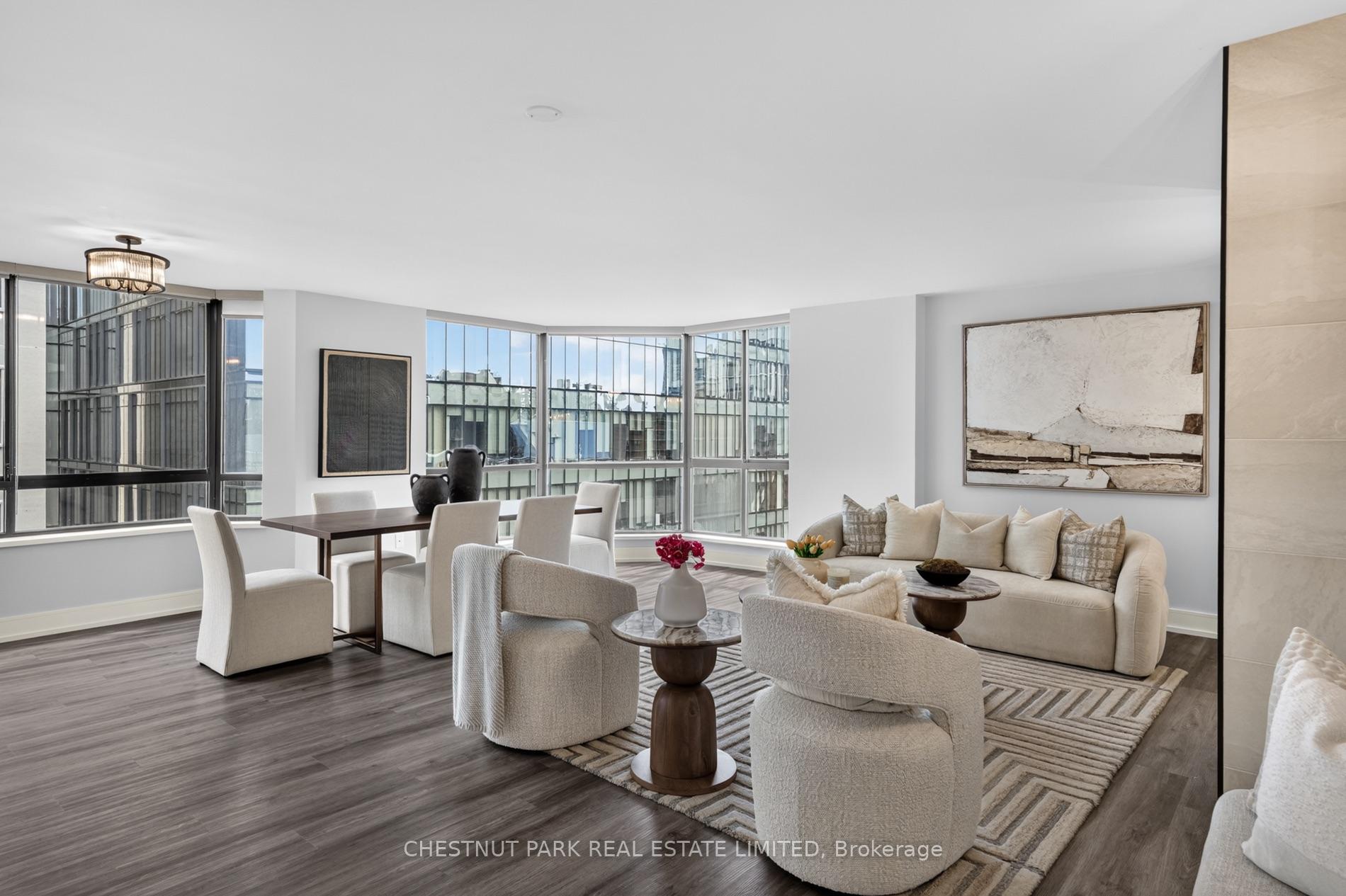 Furnished condo living and dining area with corner windows overlooking neighboring buildings.