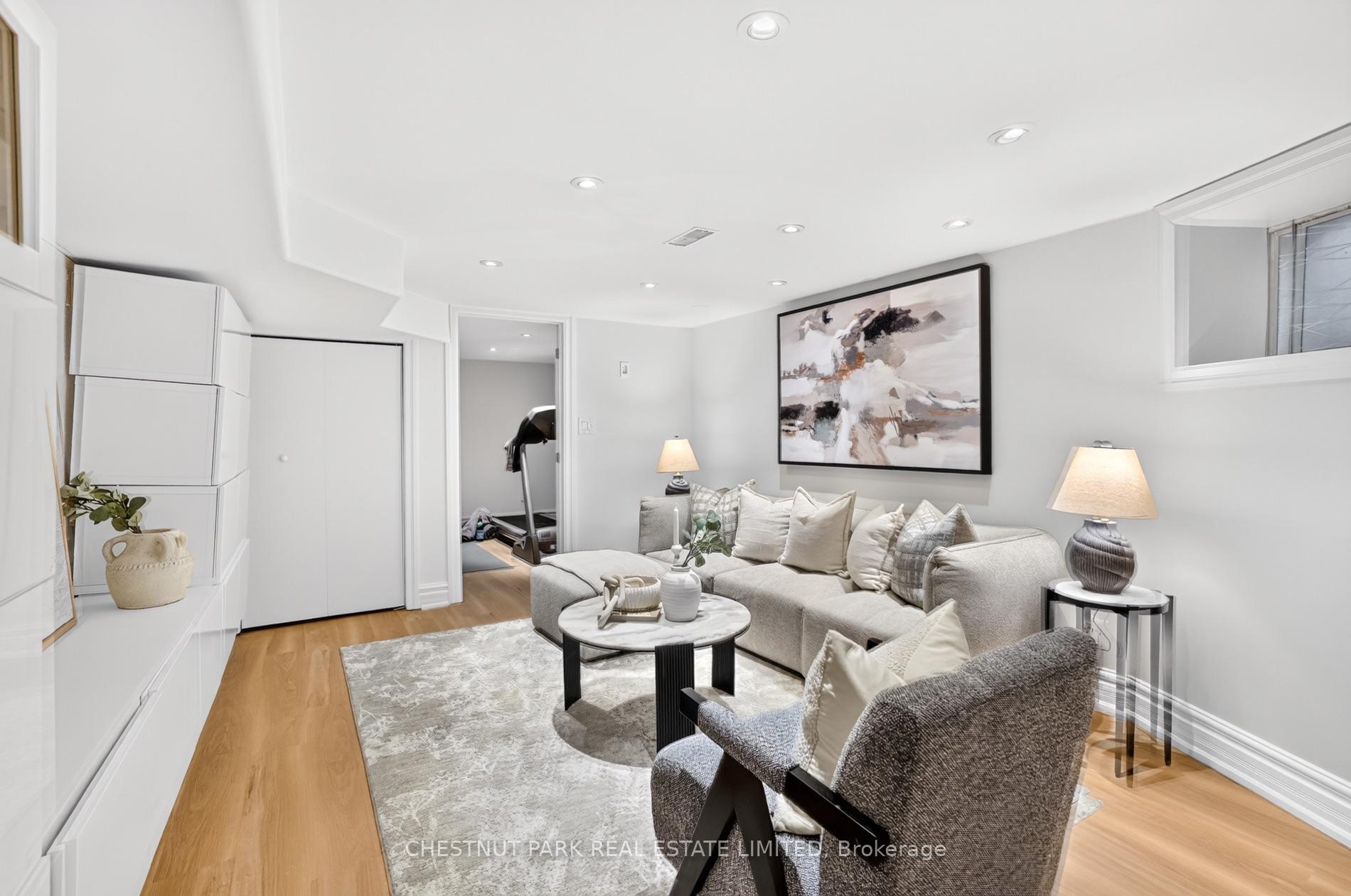 Staged living room with a cream sectional, abstract artwork, and light hardwood floors.