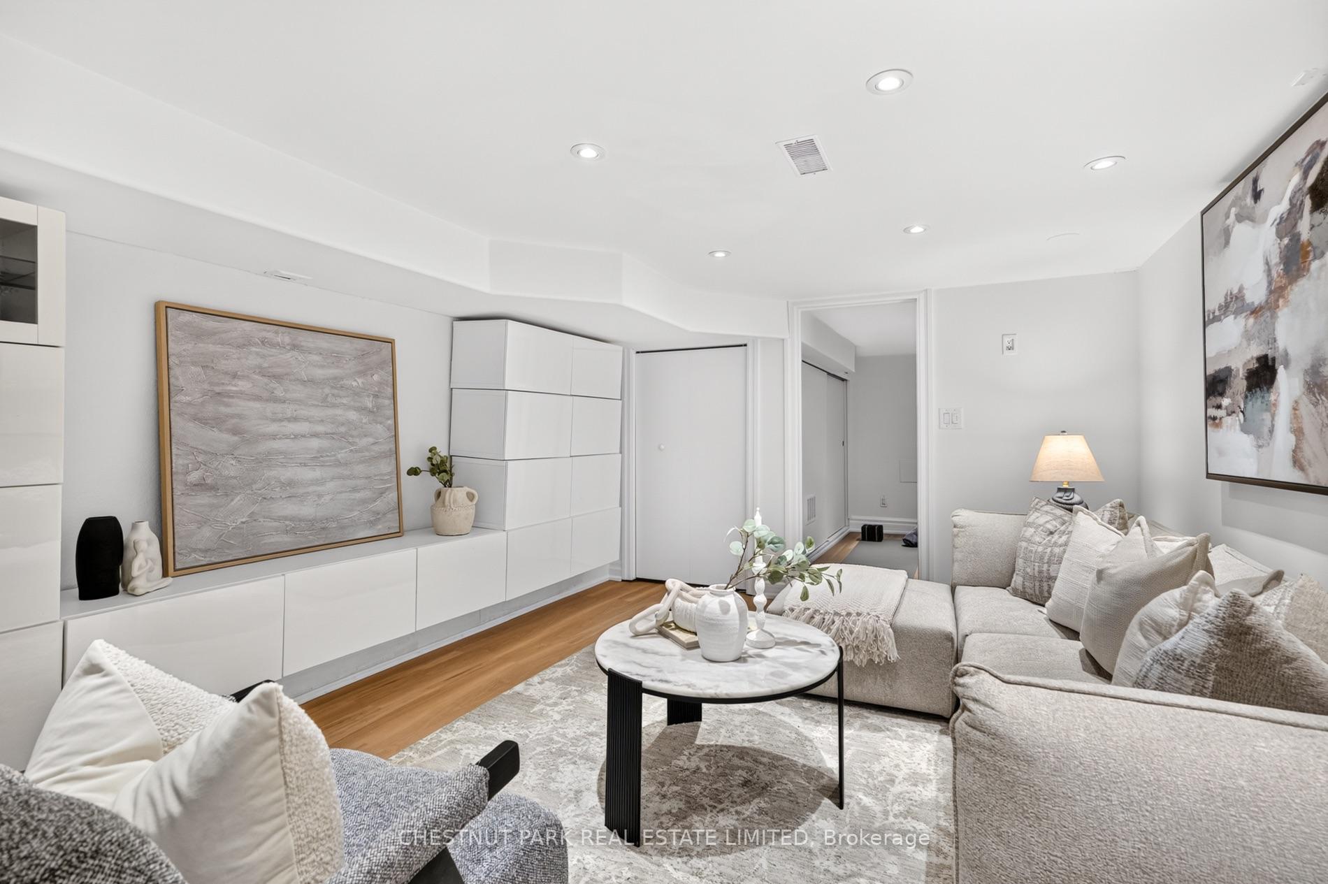 Staged living room with a light sectional, round coffee table, white built-ins, and abstract wall art.