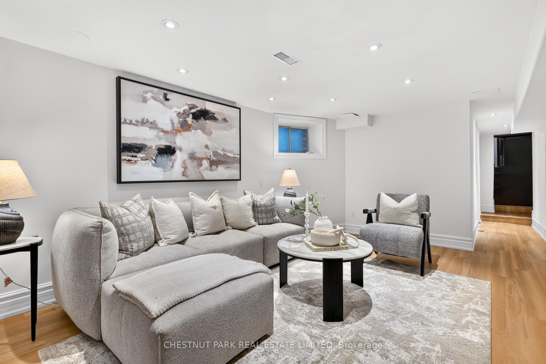 Staged living room with a gray sectional, abstract wall art, and warm wood flooring.