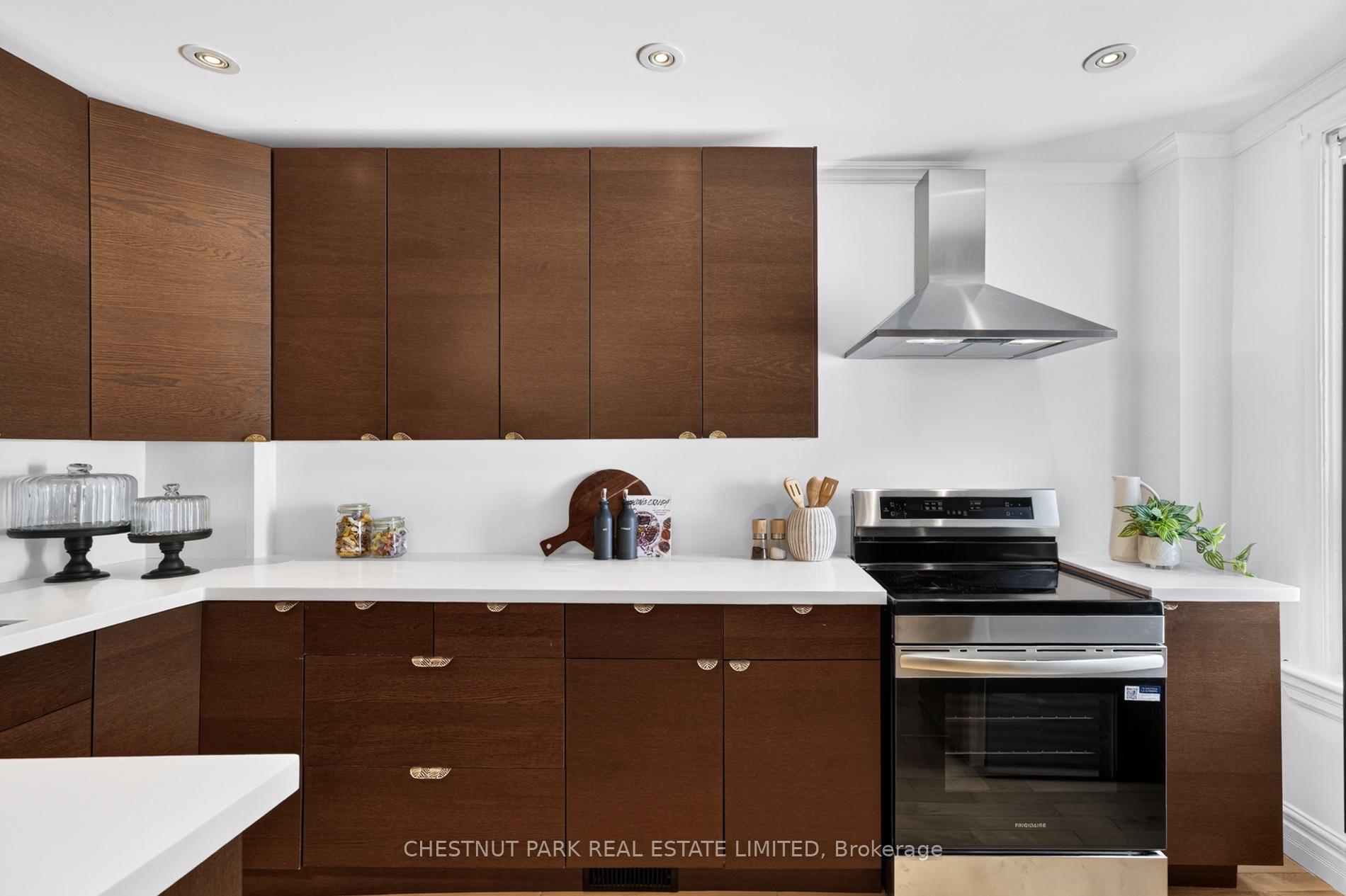 Kitchen with walnut cabinets, white counters, and a stainless steel range and hood.