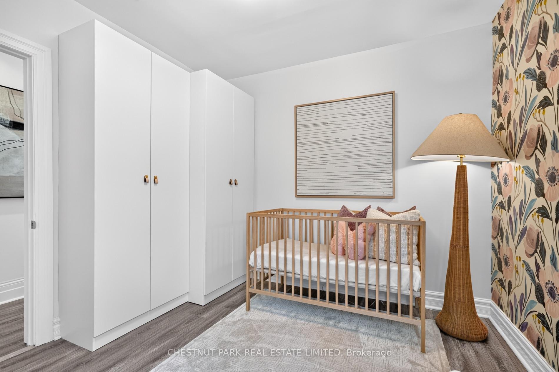 Nursery with a wood crib, white built-in wardrobes, and floral wallpaper.