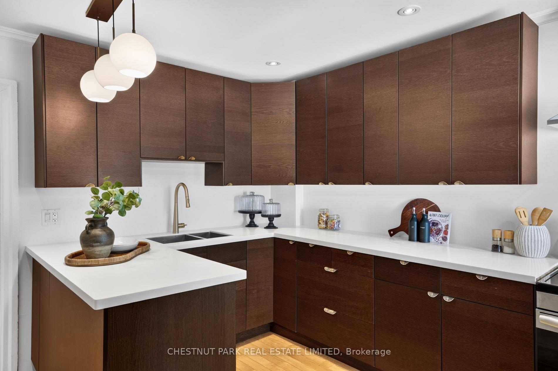 Kitchen with dark wood cabinets, white countertops, a peninsula and three globe pendant lights.