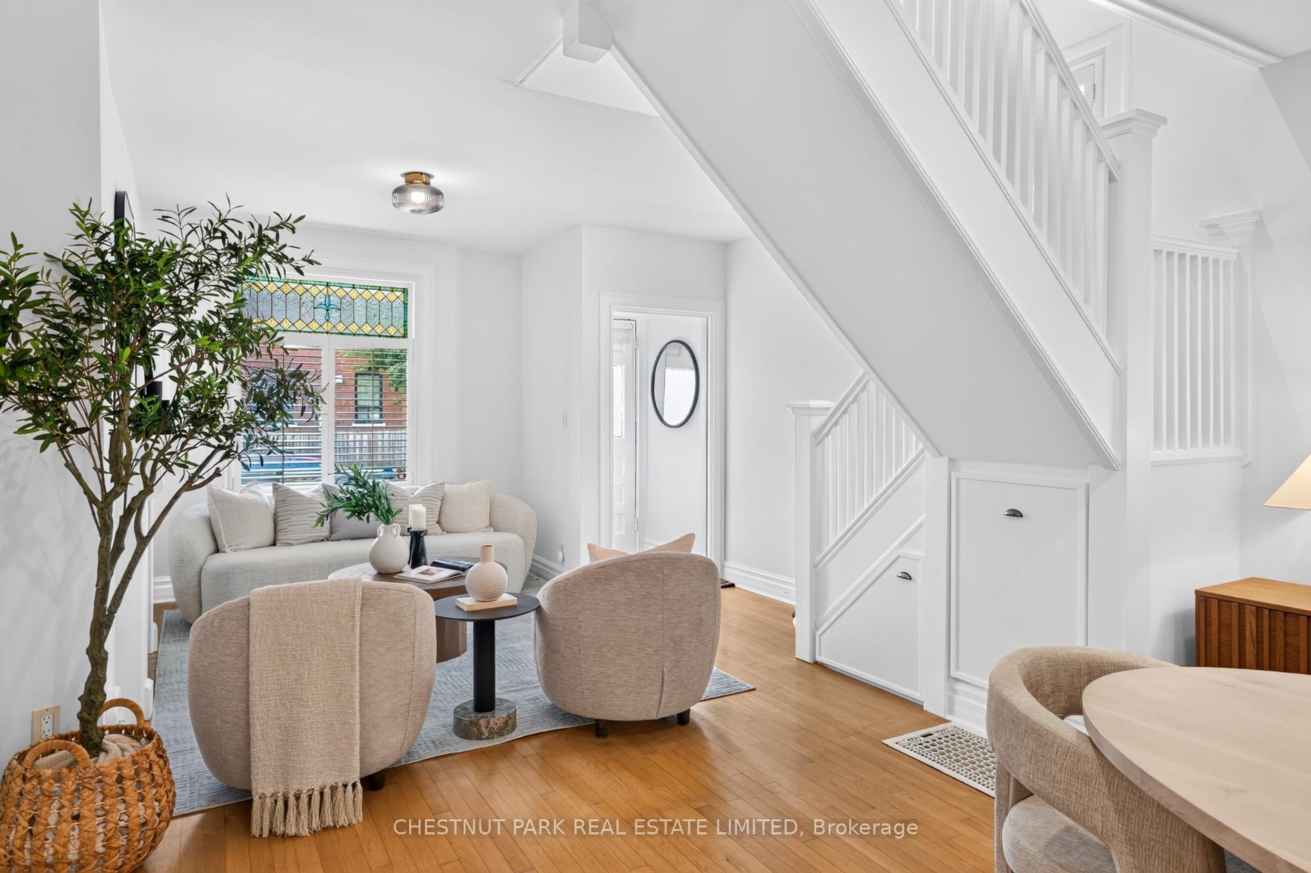 Staged living room with a stained-glass window and a prominent white staircase with built-in storage.