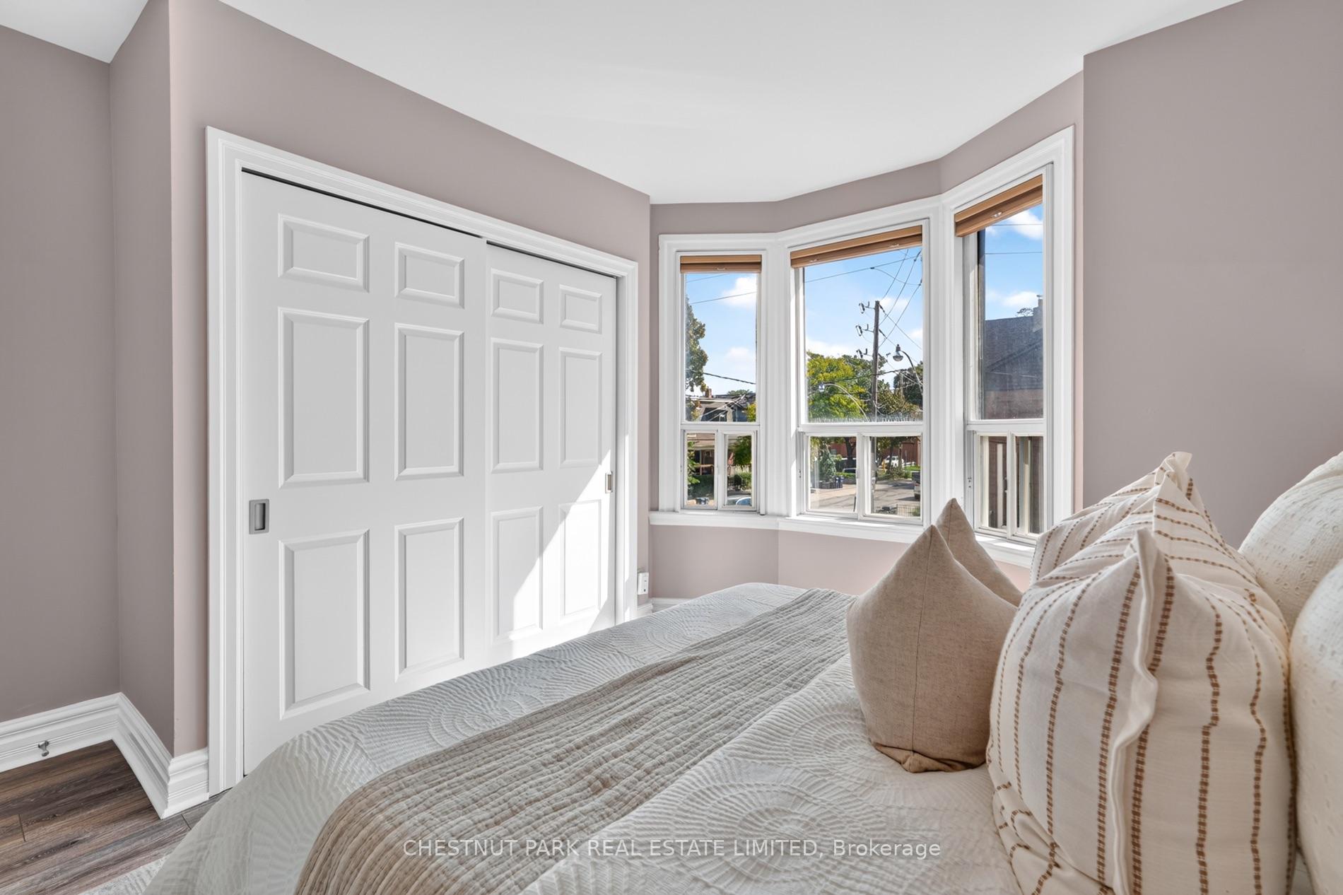 Bedroom with a quilted bed, sliding closet doors, and a bright bay window.